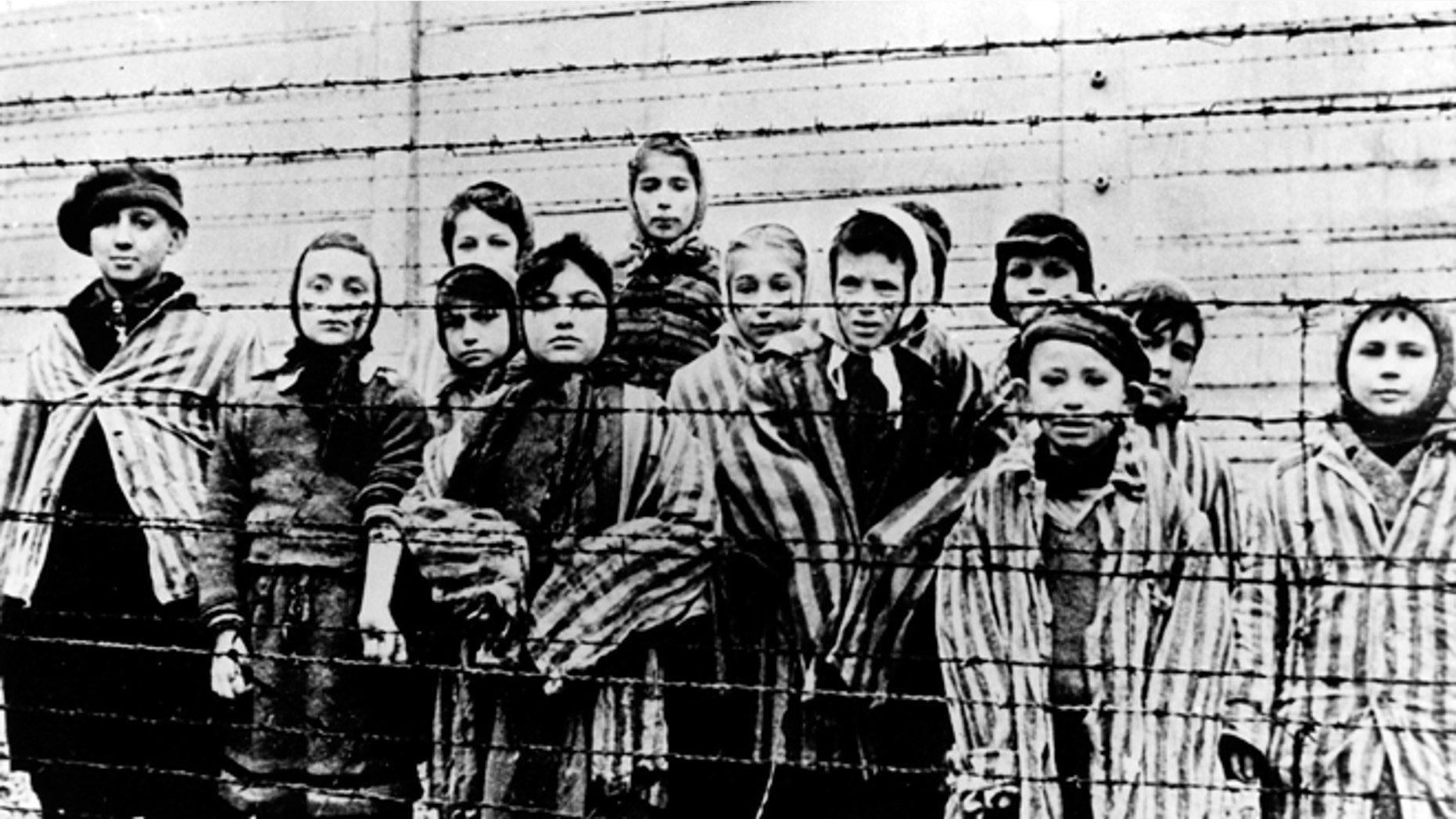 FILE - A picture taken just after the liberation by the Soviet army in January, 1945, shows a group of children wearing concentration camp uniforms behind barbed wire fencing in the Auschwitz Nazi concentration camp. (AP)