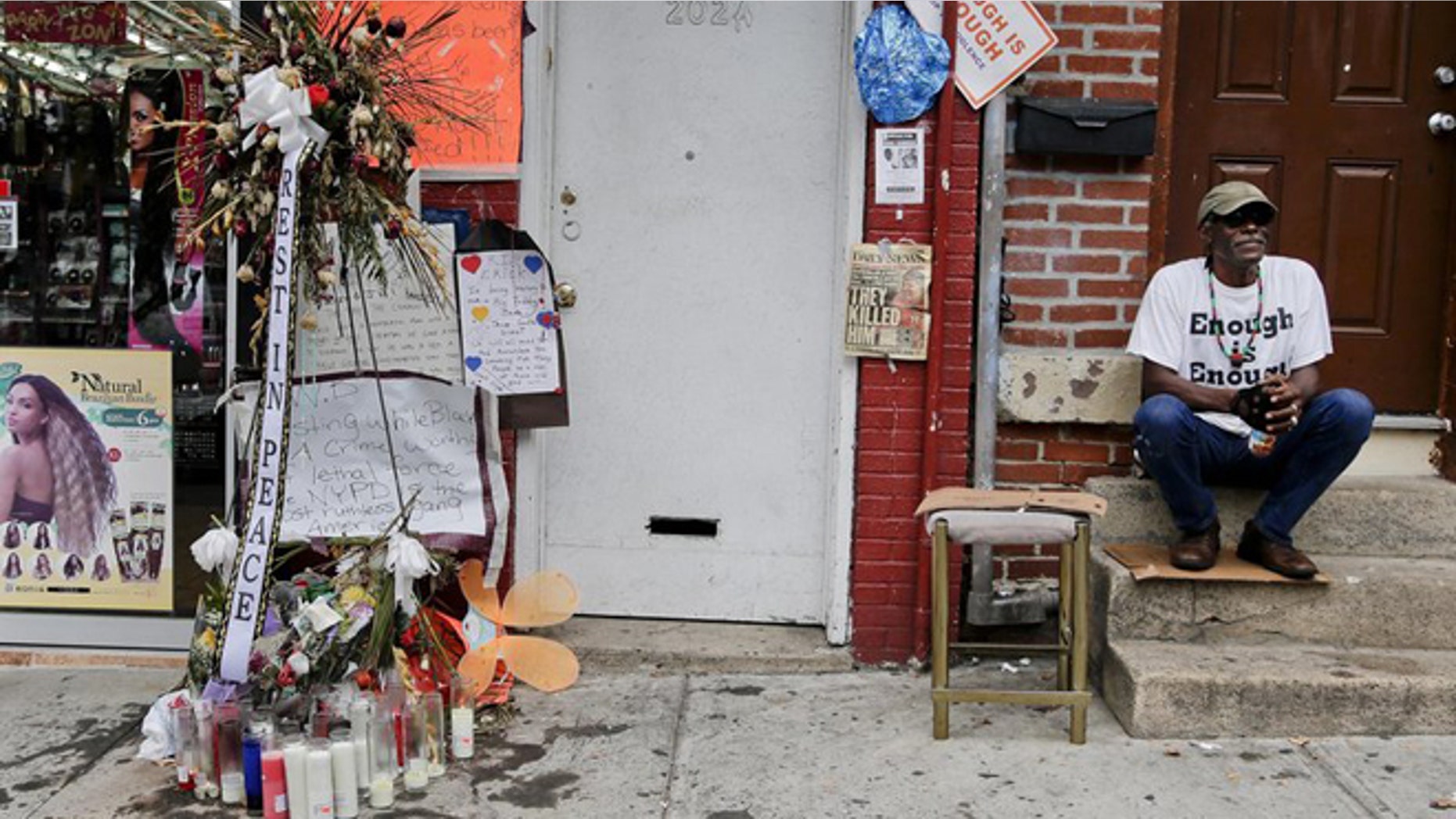 FILE: Doug Brinson sits on a stoop next to a makeshift memorial for Eric Garner in Staten Island, N.Y. Garner died after he was put in a chokehold by police officers while being arrested at the site for selling untaxed loose cigarettes. His death has been ruled a homicide.
