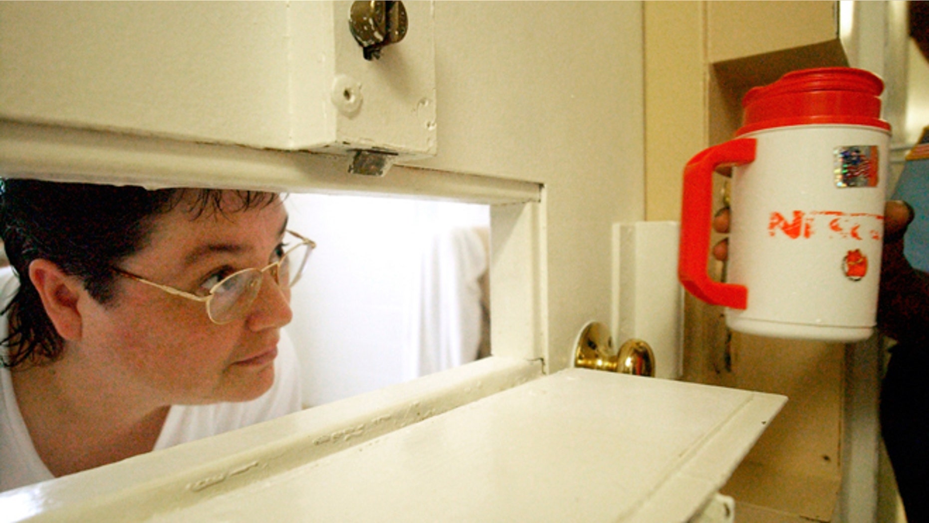 FILE -- July 6, 2004: Kelly Gissendaner, the only woman on Georgia's death row, peers through the slot in her cell door as a guard brings her a cup of ice at Metro State Prison in Atlanta. Gissendaner was convicted of murder in the February 1997 stabbing death of her husband.