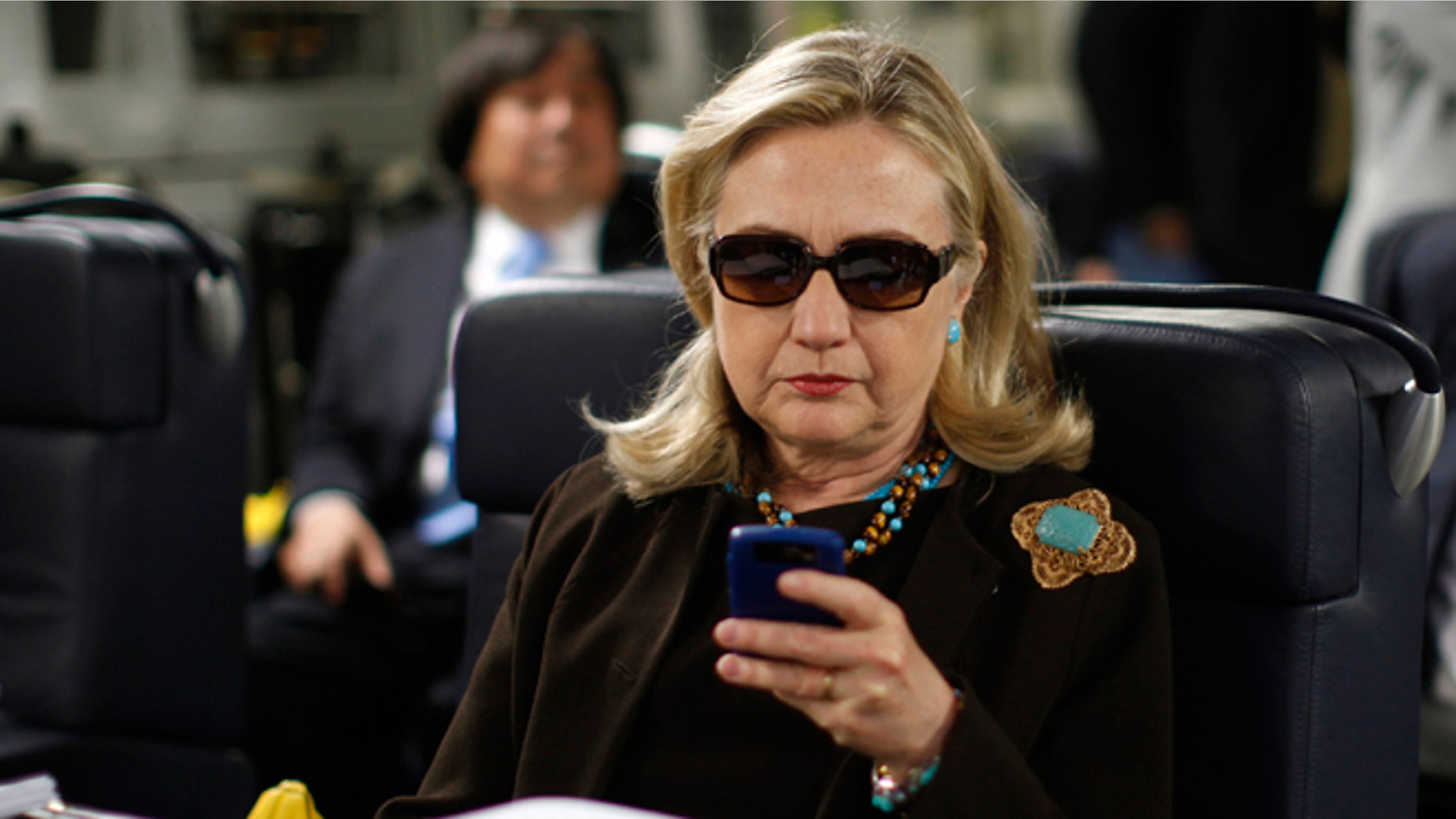 FILE - Oct. 18, 2011: Then-Secretary of State Hillary Rodham Clinton checks her Blackberry from a desk inside a C-17 military plane upon her departure from Malta, in the Mediterranean Sea, bound for Tripoli, Libya.