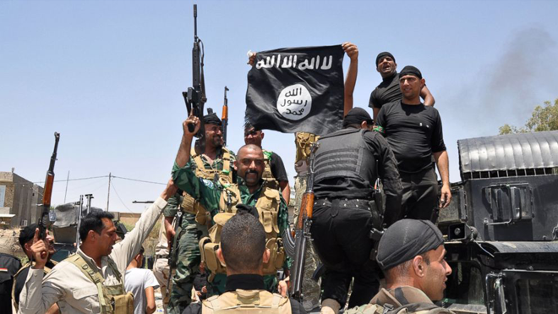 FILE -- Jun 28, 2014: Iraqi security forces hold up a flag of the the jihadist group ISIS that they captured during an operation to regain control of Dallah Abbas 35 miles outside of Baghdad, Iraq.