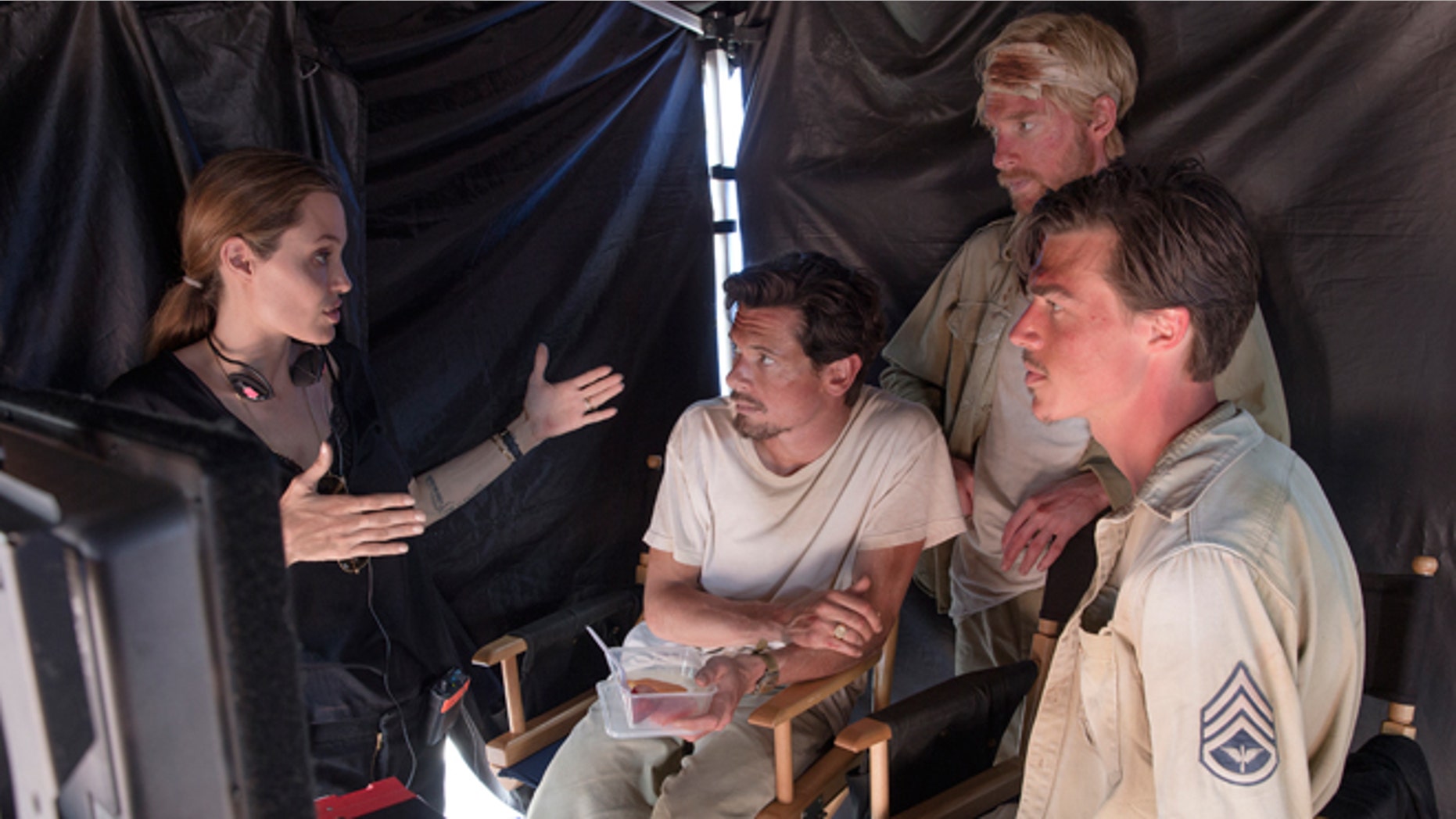 In this image released by Universal Pictures, director Angelina Jolie, from left, speaks with actors Jack O'Connell, Domhnall Gleeson and Finn Witrock on the set of "Unbroken."