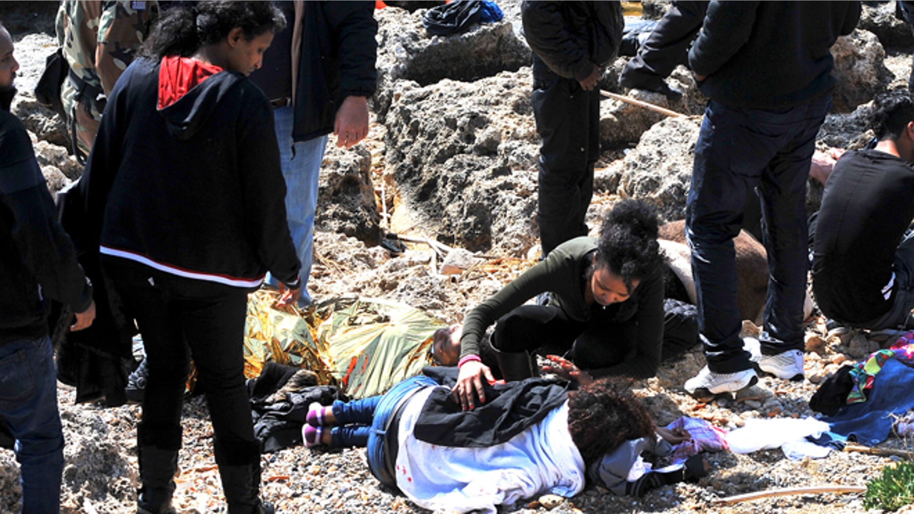 April 20, 2015 : An immigrant treats a co-traveler lying on a coast in the eastern Aegean island of Rhodes, Greece. Greek authorities said that at least three people have died, including a child, after a wooden boat carrying at least 83 migrants from the Turkish shore ran around off the island of Rhodes.
