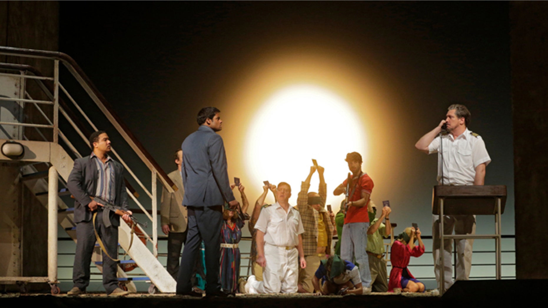 In this image released by the Metropolitan Opera, Aubrey Allicock as Mamoud, foreground from left, Sean Pannikar as Molqui, and Paulo Szot as the Captain, perform with the cast in "The Death of Klinghoffer," at the Metropolitan Opera in New York.