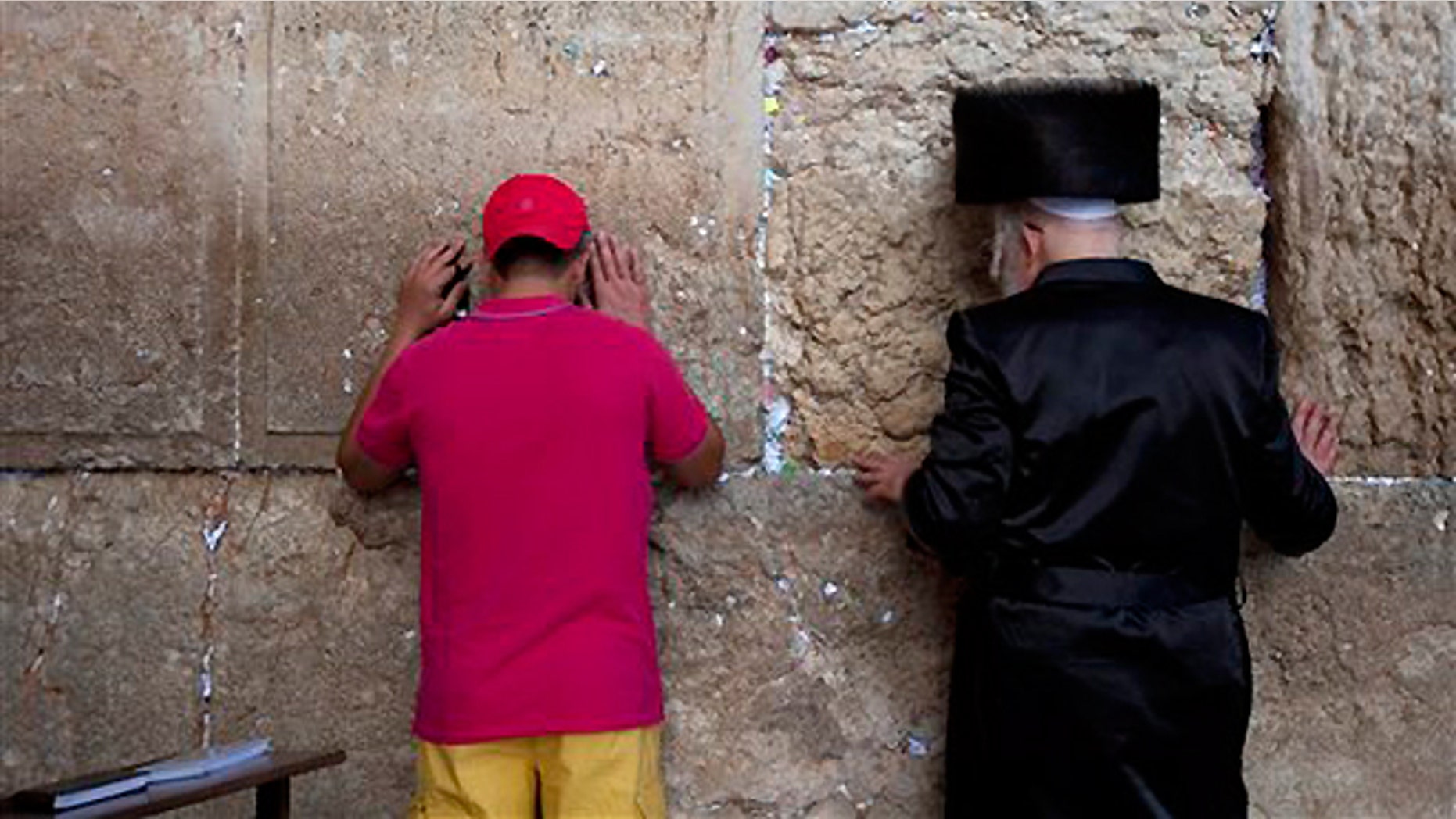 Sept. 4, 2013: An ultra-Orthodox Jewish man prays alongside a tourist ahead of the Jewish New Year at the Western Wall, the holiest site where Jews can pray in Jerusalem's old city.