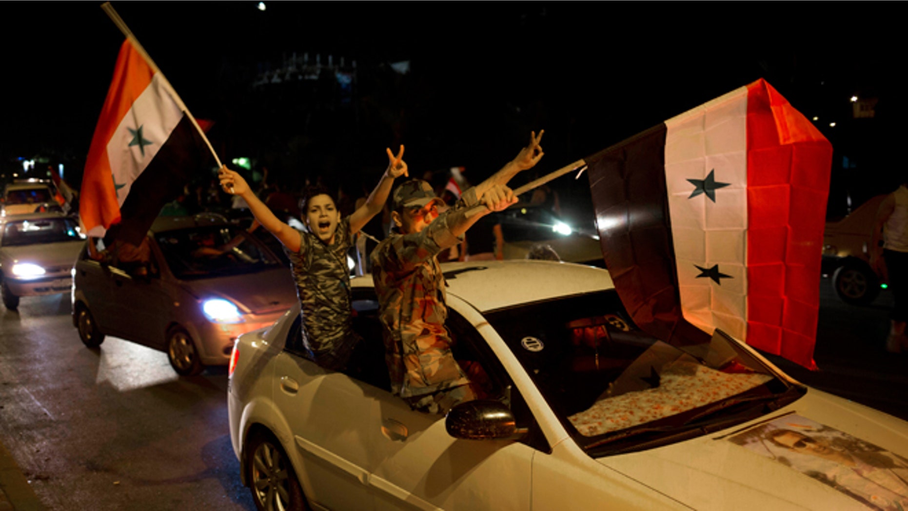 Syrian soldiers celebrate Bashar Assad's presidential re-election in Damascus, Syria, Wednesday June 4, 2014. Assad has been re-elected in a landslide, officials said Wednesday, capturing another seven-year term in the middle of a bloody 3-year-old uprising against his rule that has devastated the country.