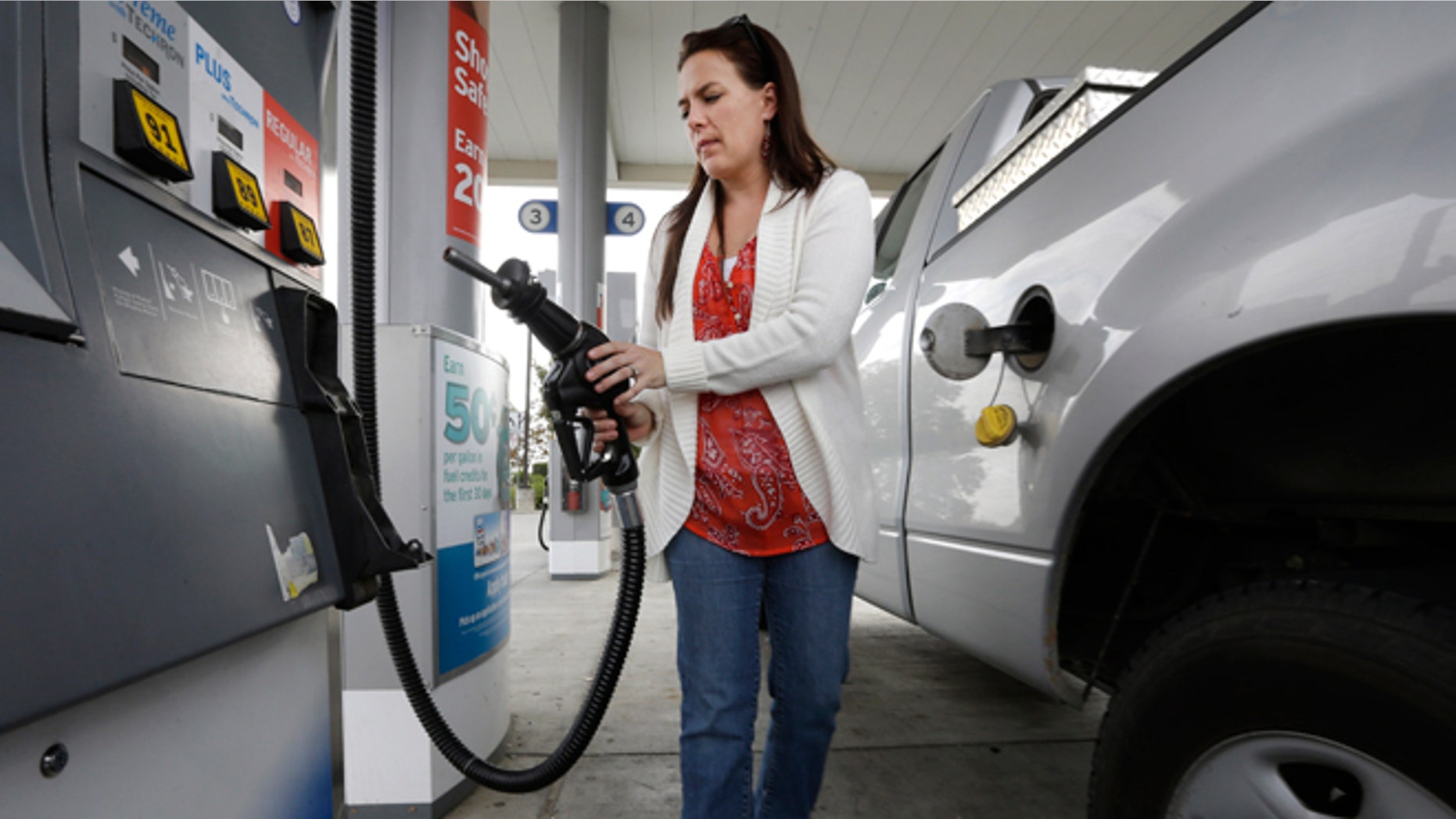 FILE -- Nov. 12, 2014: Lydia Holland replaces the gas nozzle after filling up at a gas station in Sacramento, Calif.