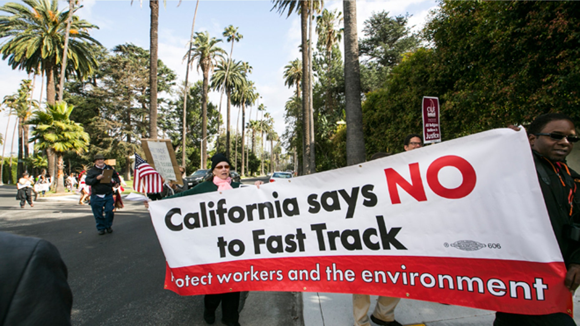 May 7, 2015: Los Angeles community members take to the streets of Beverly Hills to demand that Hillary Rodham Clinton oppose the Trans-Pacific Partnership (TPP) and Trade Promotion Authority (TPA) known as “The Fast Track,” in Beverly Hills, Calif. AP Photo/Damian Dovarganes