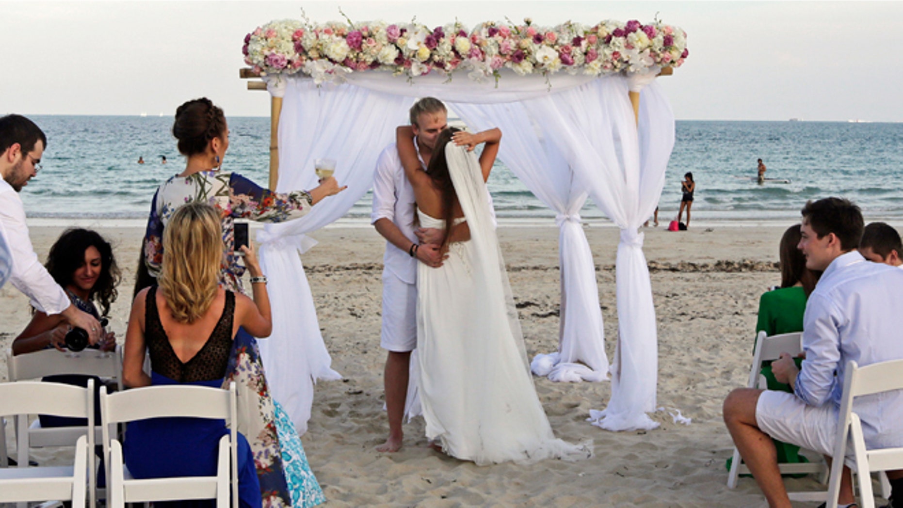 FILE -- Jan. 7, 2015: Tourists Vlad Borankin, the groom, and Daria Borankina, both of Moscow, Russia, kiss during their wedding ceremony at South Pointe area in Miami Beach, Fla.