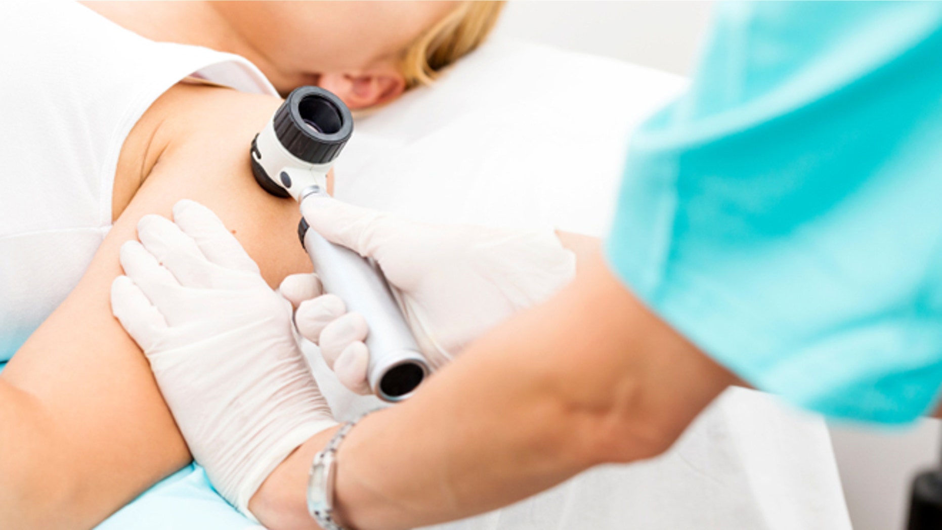Woman undergoing medical exam using dermoscope, copy space