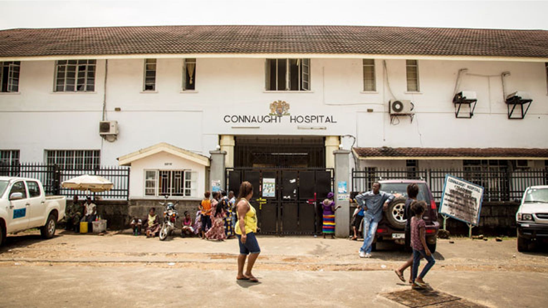 In this photo taken on Sunday, Sept. 14, 2014, people walk past the Connaught Hospital that is used for treating people suffering from the Ebola virus in Freetown, Sierra Leone.