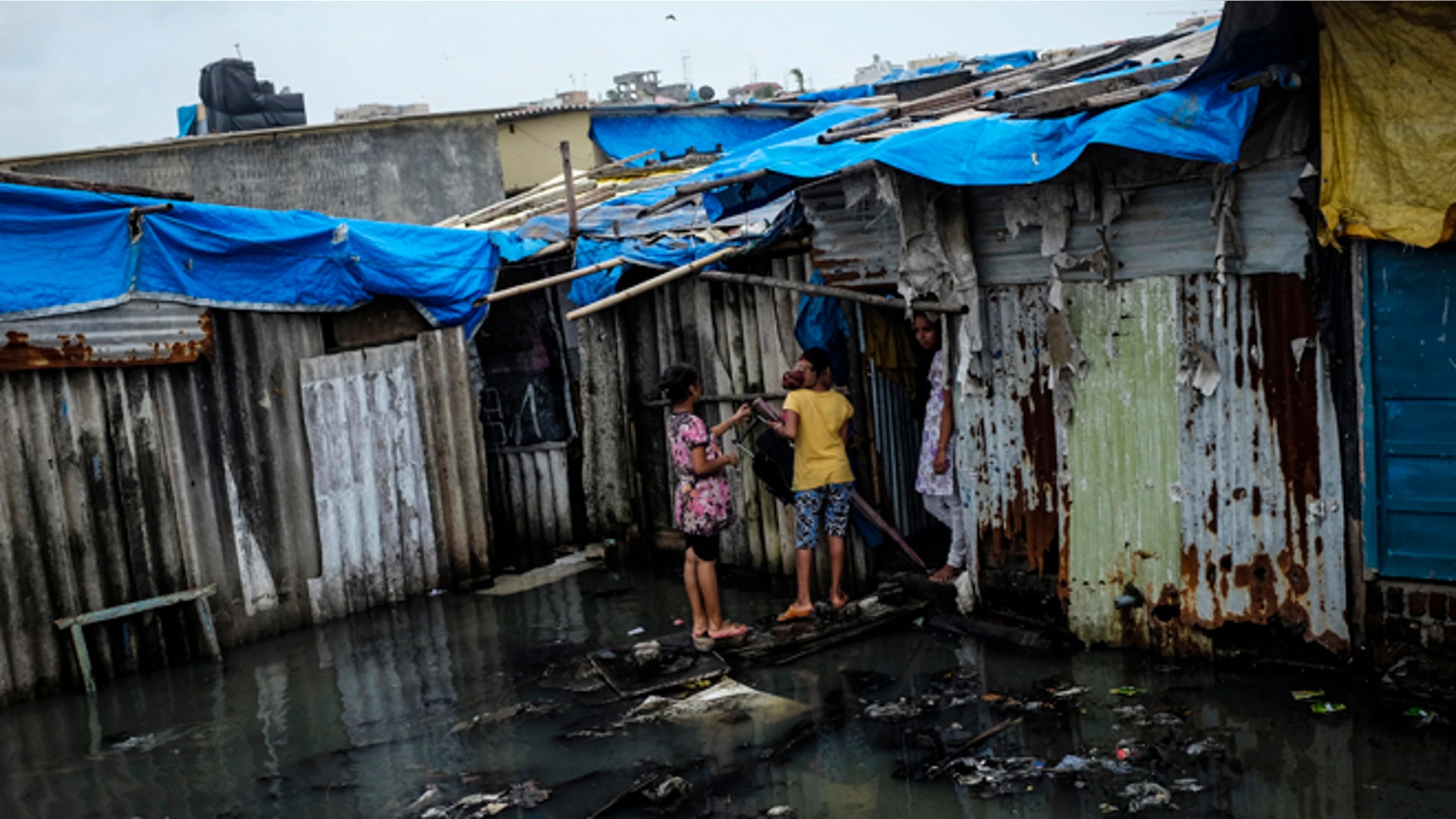Residents stand in a flooded street outside their house at a slum in Mumbai July 16, 2014. Weak rainfall in India since the start June, when the monsoon season began, has raised concerns of a first drought in five years, although weather experts are hopeful rains will revive in the next week. REUTERS/Danish Siddiqui (INDIA - Tags: SOCIETY ENVIRONMENT POVERTY) - RTR3YWFK