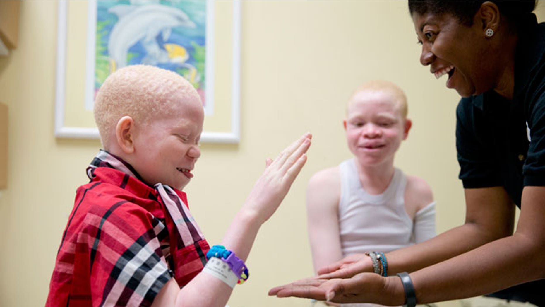 Monica Watson, right, with the Global Medical Relief Fund, plays with Mwigulu Magesa, 12, left, and Emmanuel Rutema, 13, during a fitting for prosthetic limbs at the Shriners Hospital for Children in Philadelphia on Thursday, July 23, 2015. Witch doctors often lead brutal attacks in Tanzania to use albino body parts in potions they claim bring riches.