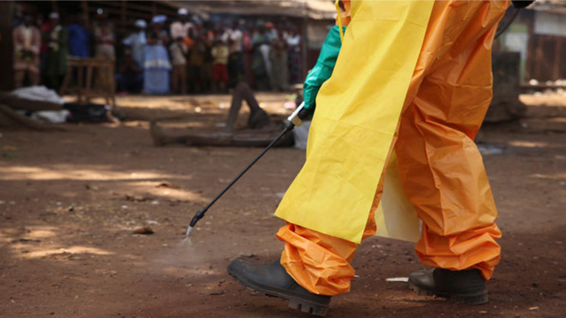 A member of the French Red Cross disinfects the area around a motionless person suspected of carrying the Ebola virus as a crowd gathers in Forecariah January 30, 2015. Health officials botched more than 20 Ebola blood tests in January and February which led to the release of at least four positive patients, two of whom later died, Guinea's anti-Ebola coordinator and other health officials told Reuters.