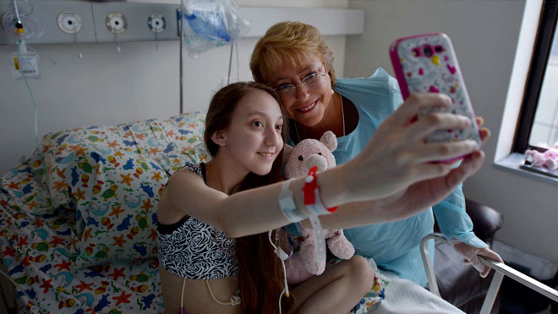 Chile President Michelle Bachelet, right, poses for a selfie with Valentina Maureira, who suffers from cystic fibrosis, at a hospital in Santiago, Chile, Saturday, Feb. 28, 2015.