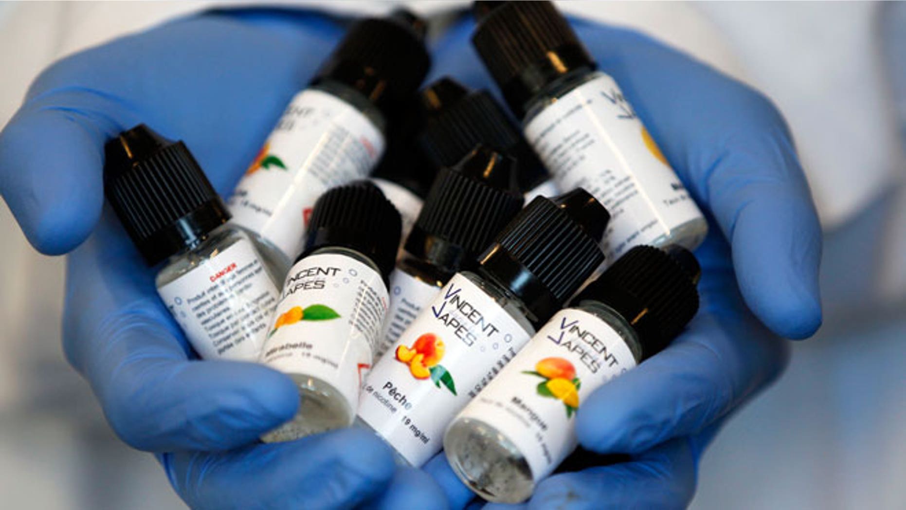 An employee displays e-liquids phials with mirabelle (plum) and mango aromas for electronic cigarettes produced at the "Vincent dans les Vapes" factory in Pessac, near Bordeaux, October 9, 2013. The European Parliament voted on Tuesday to water down proposed tobacco legislation, rejecting an immediate ban on menthol cigarettes and scaling down the size of health warnings on packets following intense lobbying by tobacco companies. The parliament also said manufacturers should be free to sell smokeless e-cigarettes, which deliver nicotine electronically and are a rapidly growing market, as a consumer product when not being marketed as an aide to help people quit smoking.