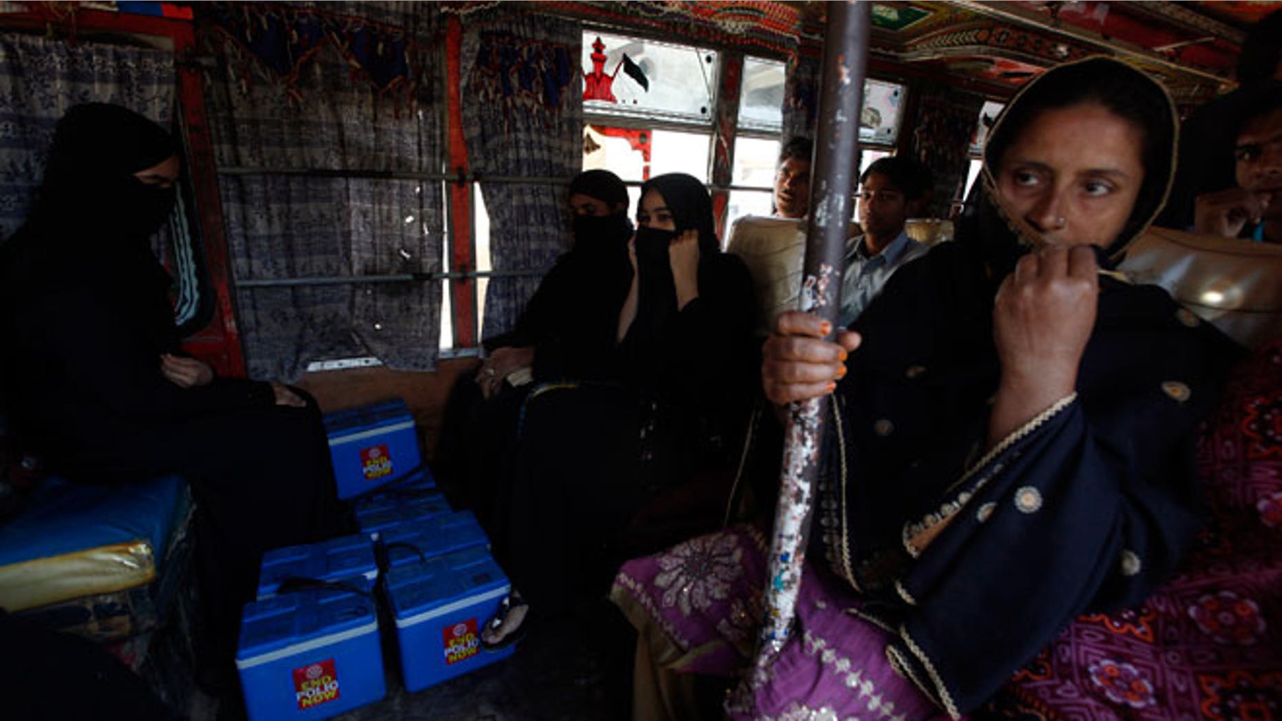 Polio vaccinators sit with boxes of the vaccine in a bus as they leave to administer it to children in different parts of Karachi October 21, 2014. Taliban militants have long been the scourge of Pakistan's polio vaccination campaign, attacking aid workers and the police who protect them as they distribute doses to children. But experts say there is another reason for the sharp spike in cases of the crippling disease in Pakistan this year - government mismanagement.