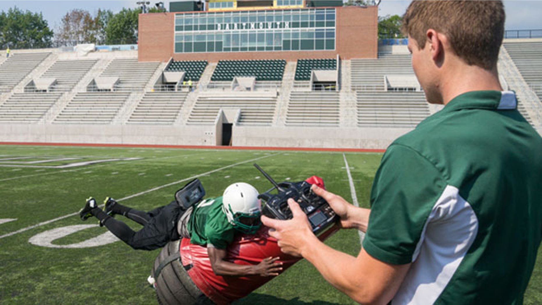 Victor Williams ’16 tackles the Mobile Virtual Player, which he and his teammates will use at practice. Quinn Connell ’13, Thayer ’14, controls the device, which he and other Thayer engineers helped develop.