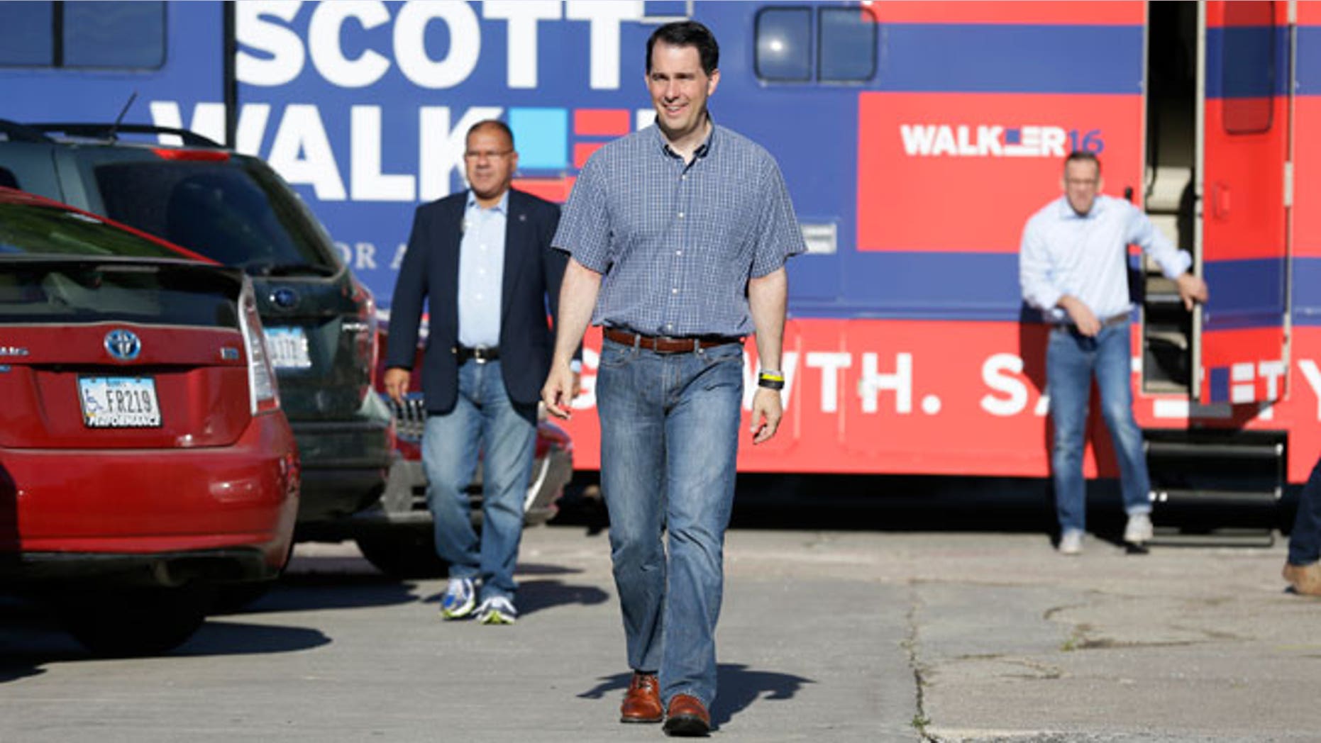 In this July 31, 2015, file photo, Republican presidential candidate Wisconsin Gov. Scott Walker walks from his campaign bus to meet with local residents at Tom and Tiff's diner, in Glenwood, Iowa. Walker is counting steps on his FitBit. Jeb Bush swears by a paleo diet. Bobby Jindal is a self-proclaimed "gym rat." With long travel days and a fresh slab of cherry pie never far away, the campaign trail is a notoriously unhealthy place to live.