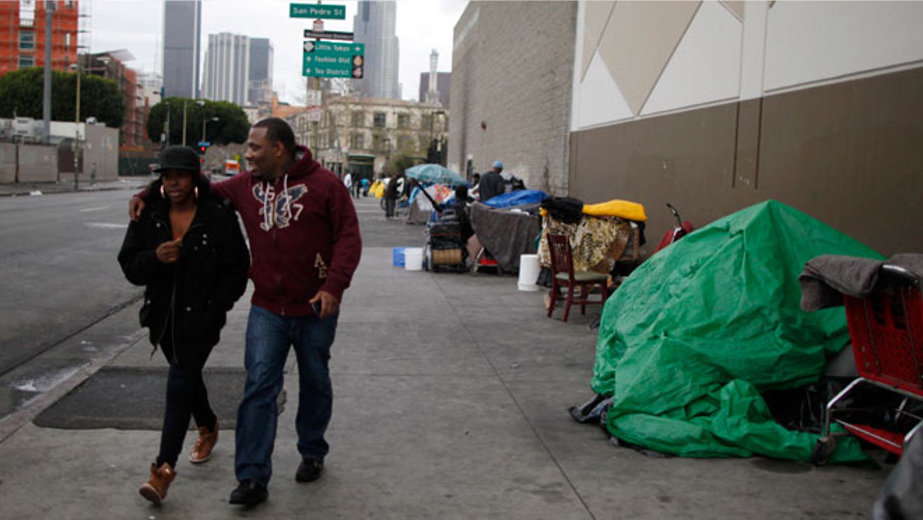 A couple walks past tents on downtown Los Angeles' Skid Row, March 7, 2013. Los Angeles has asked the U.S. Supreme Court to allow police and city workers to seize or destroy property that homeless people leave unattended on sidewalks, saying Skid Row homeless encampments presented a public-health risk. According to the Los Angeles County Department of Public Health, some 11 people have died from tuberculosis since 2007, and of the 78 people infected, 60 were homeless.