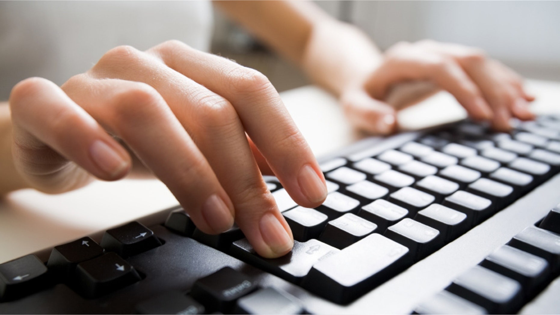 Close-up of female hands touching buttons of black computer keyboard