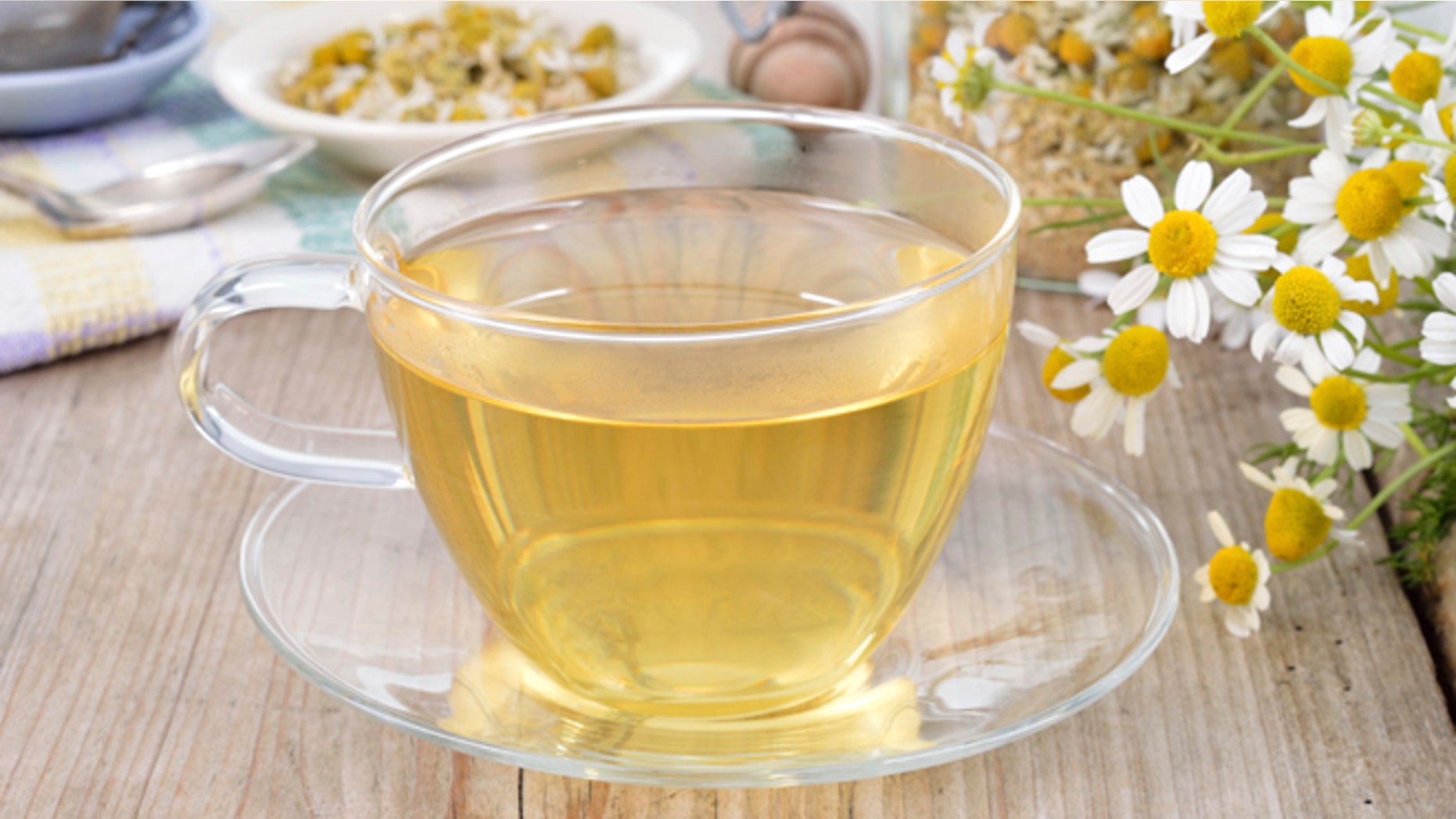 Cup of herbal chamomile tea on a wooden table. Chamomile tea in a transparent cup and camomile flowers on wooden table. Herbal tea for baby's stomach.