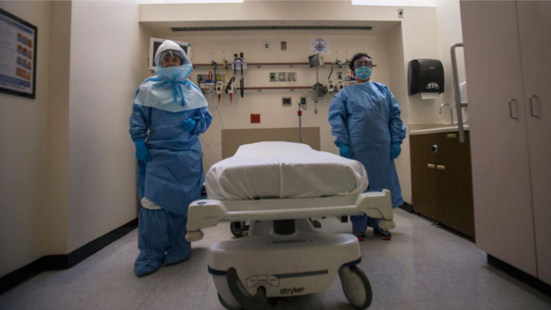 Health care workers display protective gear, which hospital staff would wear to protect them from an Ebola virus infection, inside an isolation room as part of a media tour in the emergency department of Bellevue Hospital in Manhattan, New York October 8, 2014.