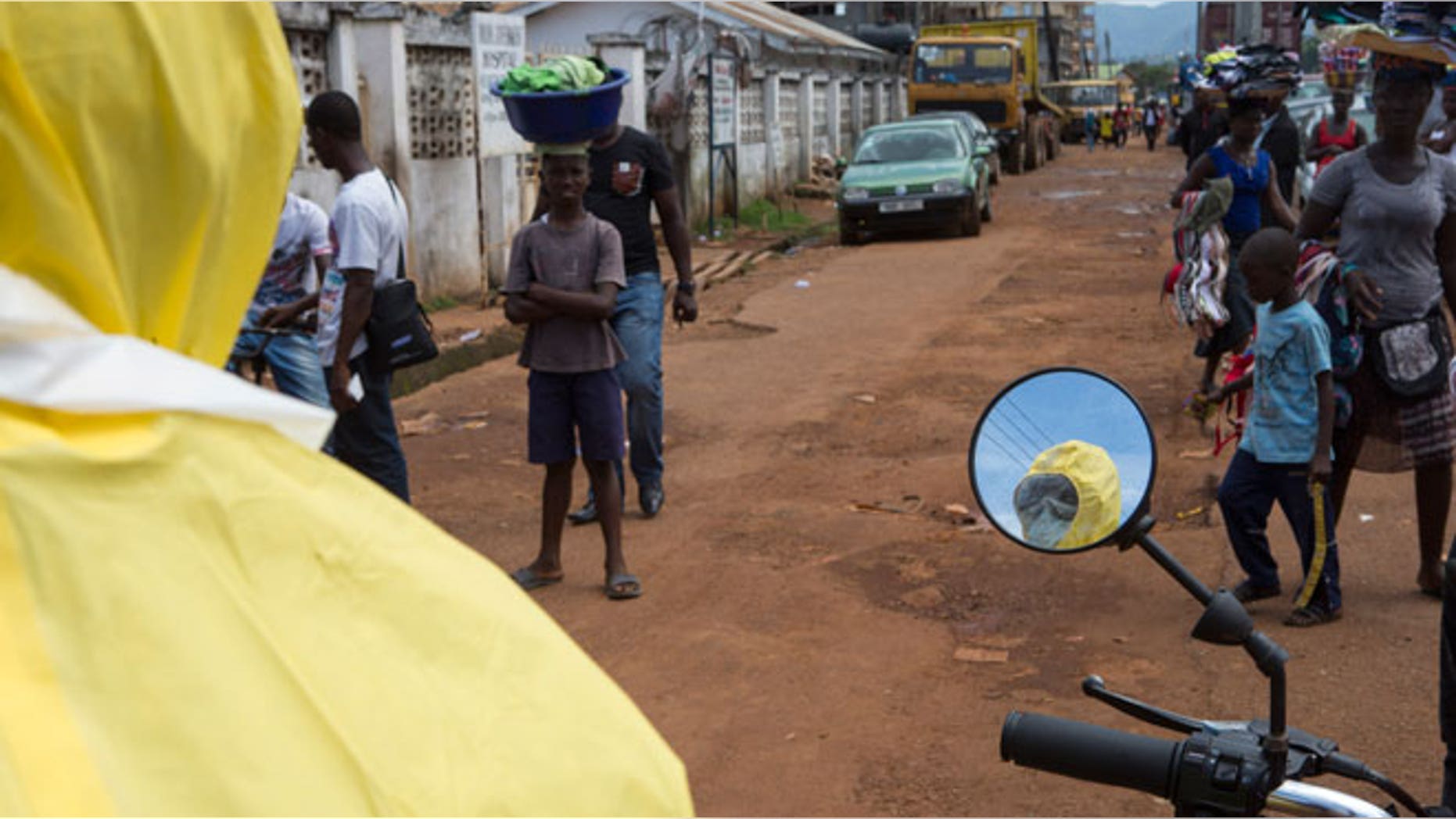 A health worker is reflected in a mirror as he prepares protective equipment near Rokupa Hospital, Freetown October 6, 2014.