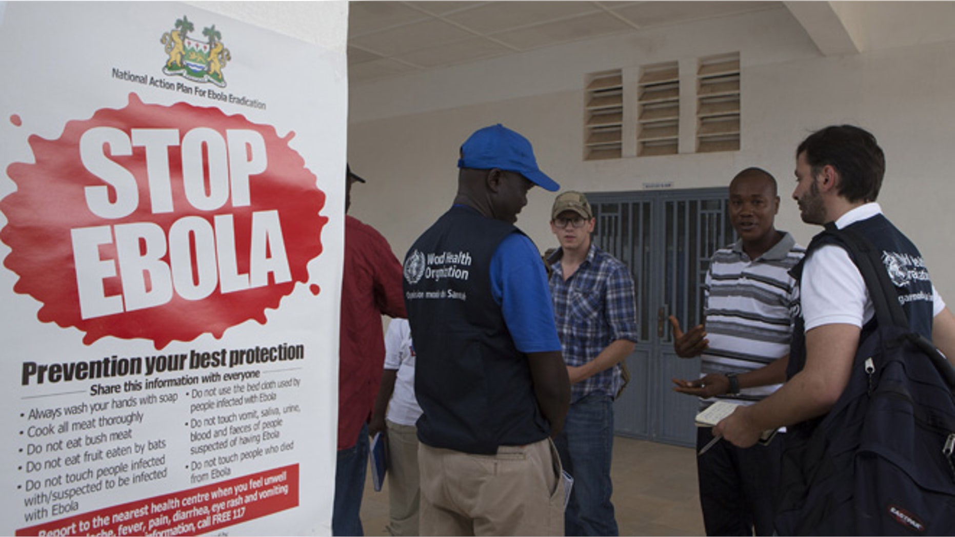 Sept. 27, 2014: WHO members and health directors stand outside the Port Loko District Hospital where the maternity ward has been converted into an isolation holding centre for people with suspected cases of the Ebola virus.