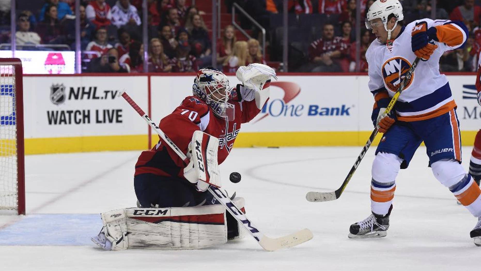 Washington Capitals goalie Braden Holtby (70) makes a save off a shot by New York Islanders right wing P.A. Parenteau (17), during second period of an NHL preseason hockey game, Sunday, Oct. 9, 2016, in Washington. (AP Photo/Molly Riley)