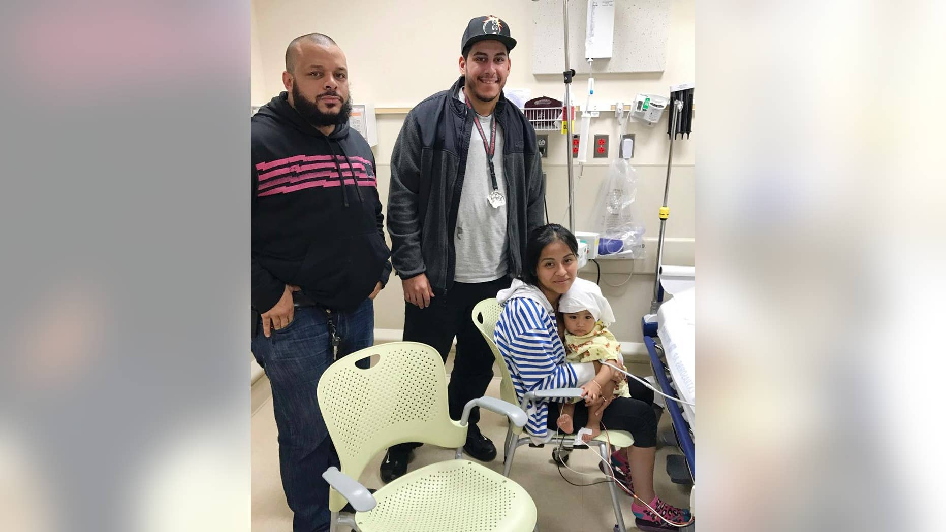 In this Oct. 14, 2016 photo released by the New York City Police Department, officers Felix Baez, left, and Giovanni Laguna pose for a photo with Liliana Benigno, and her one-year-old baby Ashley Delores, at Lincoln Hospital in The Bronx borough of New York. The officers were on patrol Friday night when they saw the Benigno running with her child down the street yelling "help" in Spanish. Seeing that the child was unresponsive, Laguna placed the baby on the ground and began CPR while Baez called for an ambulance. Police say after a minute of CPR, the baby's eyes opened and Laguna felt a faint pulse. (New York City Police Department via AP)