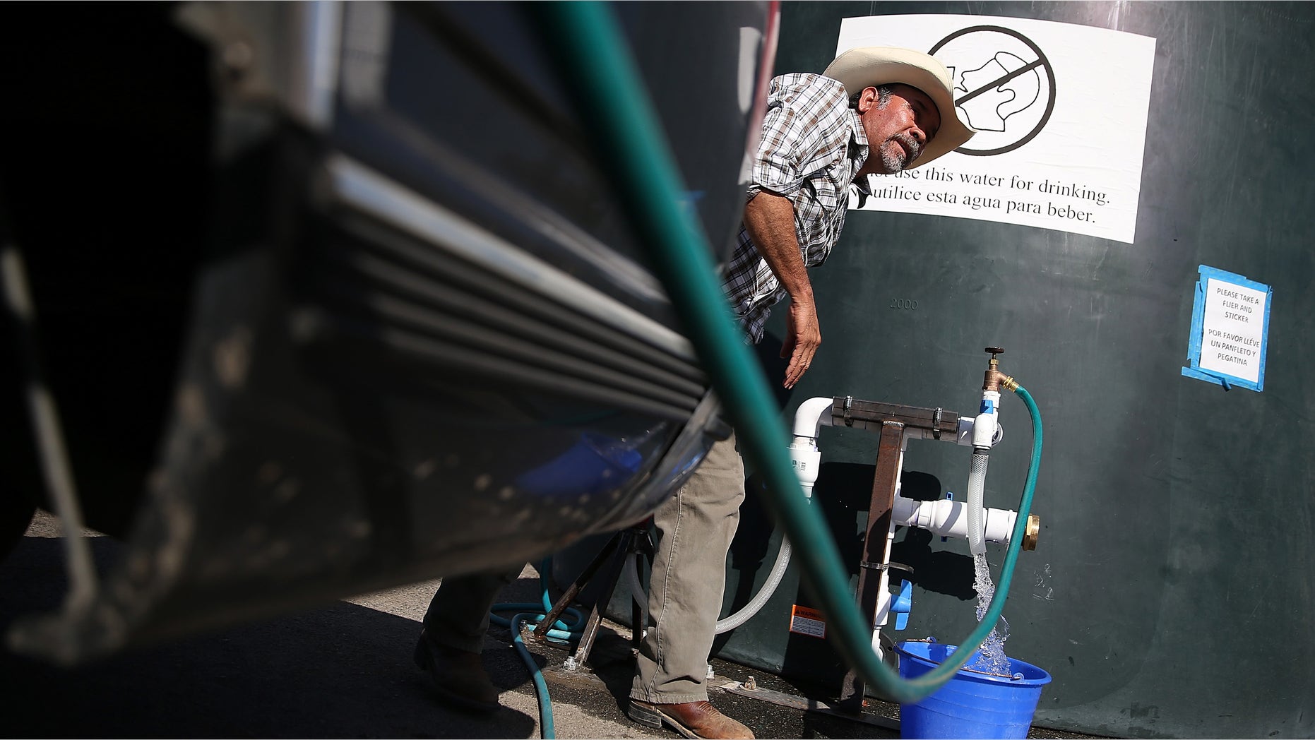 PORTERVILLE, CA - SEPTEMBER 04: Mario Garcia fills buckets with non-potable water from a tank set up in front of the Doyle Colony Fire Station on September 4, 2014 in Porterville, California. More than 300 homes in the California central valley city of Porterville have been without running water for weeks after their wells ran dry due to the severe drought. County officials and charitable organizations are providing drinking water and non-potable water for use in washing dishes and bathing. (Photo by Justin Sullivan/Getty Images)