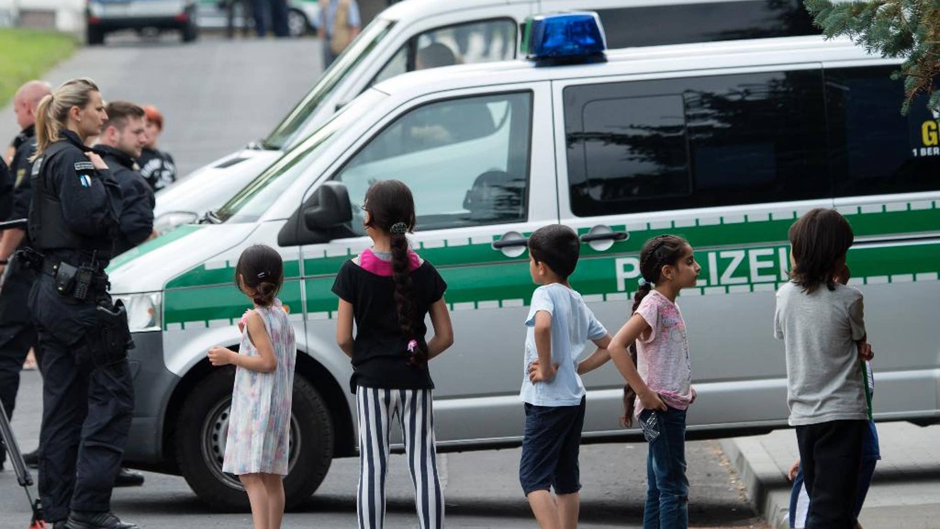 FILE - In this June 26, 2015 file photo Refugee children stand in front of a police car near the accommodation for immigrants in Freital near Dresden, eastern Germany. The head of the German Police Union is calling for a ban on demonstrations within a kilometer of centers housing refugees amid a string of violent incidents. Germany is seeing a rise in anti-foreigner attacks and vandalism amid a spike in asylum applications, which are expected to double this year. (AP Photo/Jens Meyer)