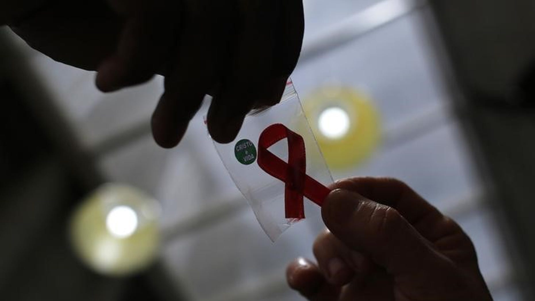 Nurse gives a red ribbon to a woman to mark World Aids Day at the entrance of Emilio Ribas Hospital, in Sao Paulo