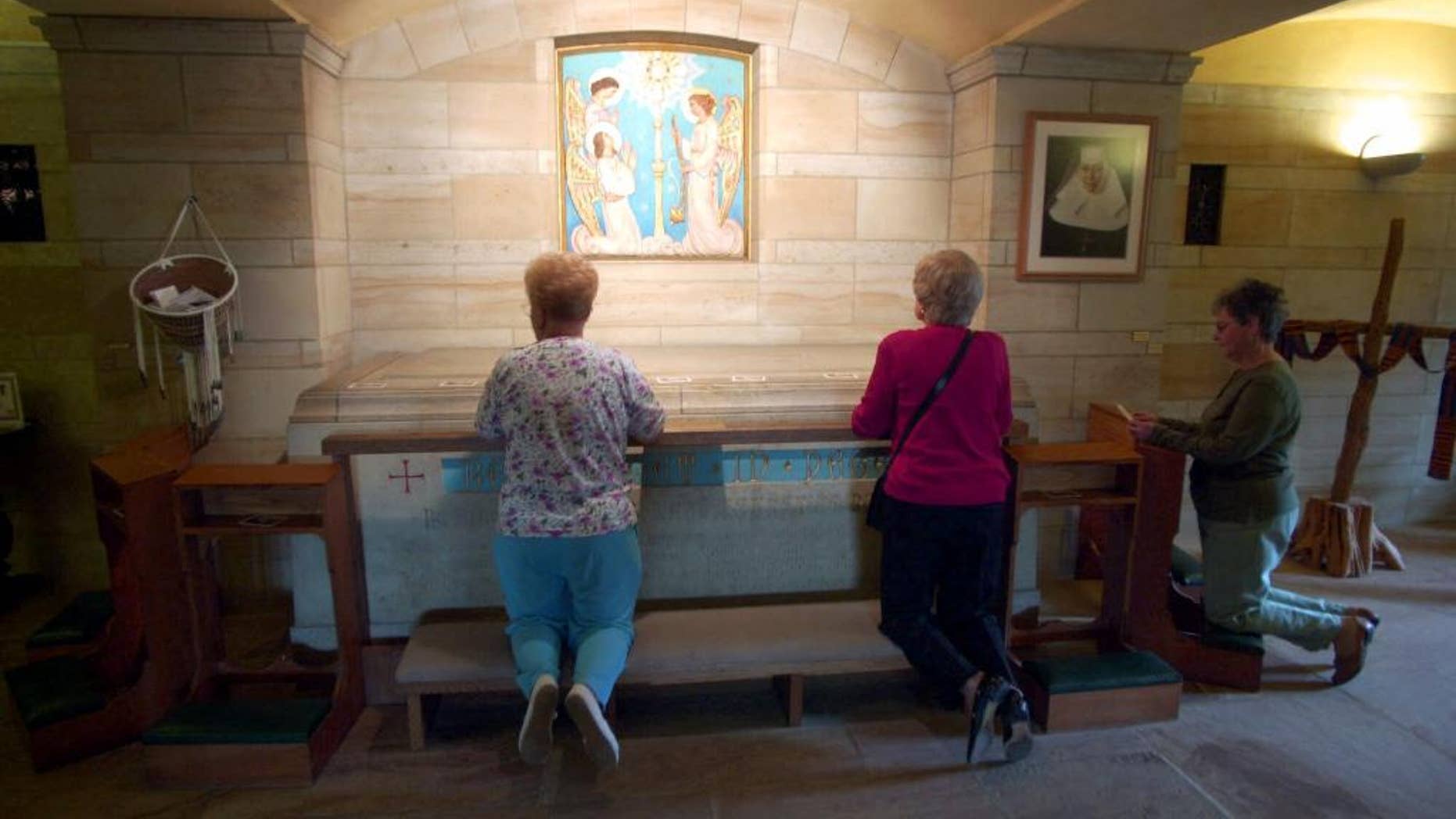 FILE - In this Oct. 2, 2000, file photo, worshippers kneel at the crypt of Saint Katharine Drexel a day after she was canonized at the Vatican as the second American-born saint, at her national shrine on the Sisters of the Blessed Sacrament's suburban Philadelphia estate in Bensalem, Pa. The Roman Catholic religious order, founded by Drexel in 1891, announced Tuesday, May 3, 2016, that it is selling the estate and plans to keep the shrine open through 2017, before moving the tomb to the Cathedral Basilica of Saints Peter & Paul in Philadelphia. The order will also sell 2,000 acres in Powhatan, Va., the site of two now-closed schools for black students. (AP Photo/Dan Loh, File)