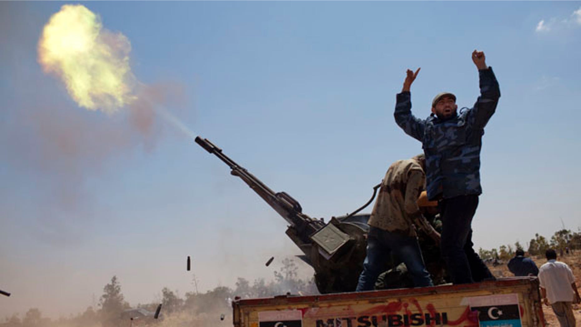May 7: A rebel fighter gestures as an anti-aircraft gun fires into the sky in a gesture to salute the dead, during the funeral of three rebel fighters killed by Muammar al-Qaddafi forces, Benghazi, Libya.