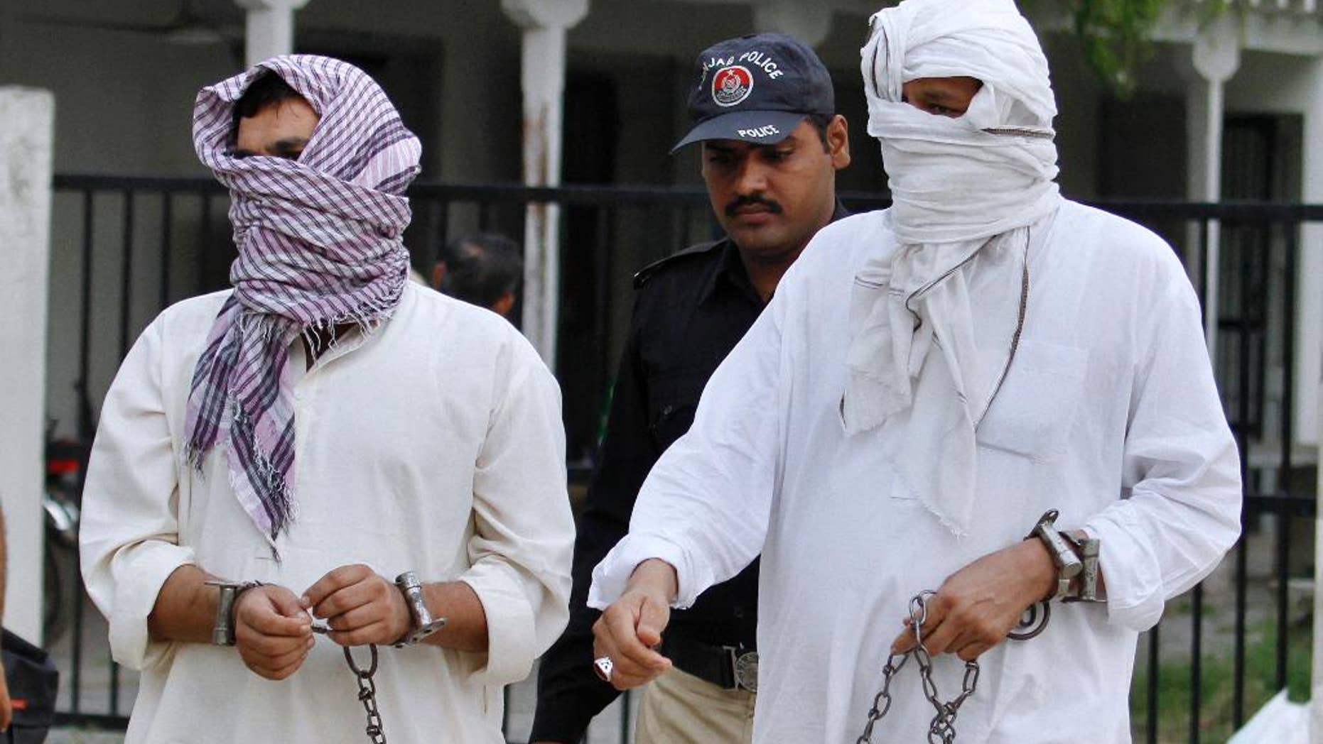 FILE - In this Friday, Sept. 23, 2016 file photo, a Pakistani police officer escorts father Mohammad Shahid, right, and ex-husband Mohammad Shakeel of slain British-Pakistani woman Samia Shahid to a court in Jhelum, Pakistan. A defense lawyer says Tuesday, Sept. 27, 2016 that Pakistani court has opened the trial against the father and ex-husband of a British woman over her alleged rape and murder in the name of so-called honor. (AP Photo/Anjum Naveed, File)