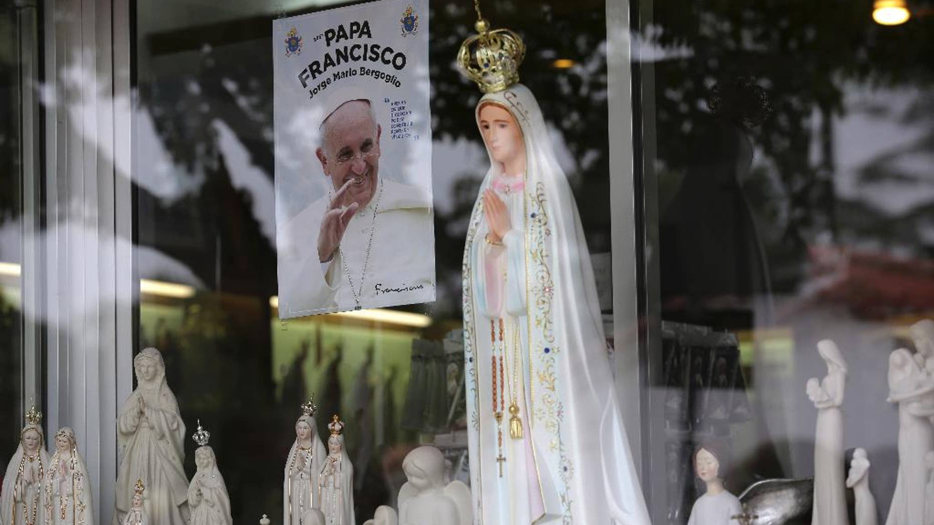 In this photo taken May 4 2017, a photo of Pope Francis, Francisco in Portuguese, is displayed on the window of a shop selling statues of Our Lady of Fatima in the village of Fatima, Portugal. Pope Francis is visiting the Fatima shrine on May 12 and 13 to canonize two Portuguese shepherd children who say they saw visions of the Virgin Mary 100-years ago. (AP Photo/Armando Franca)