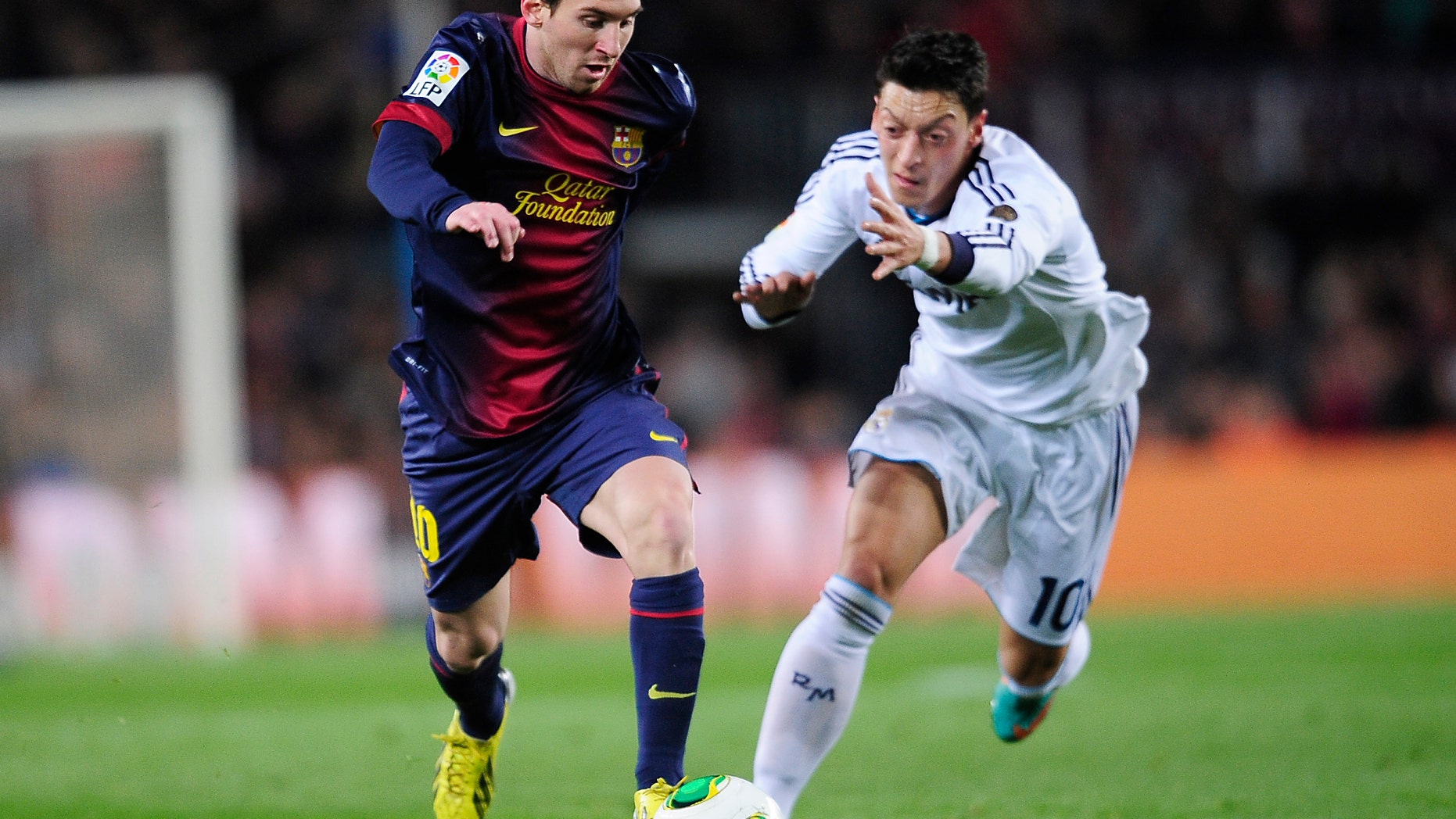 Barcelona's Lionel Messi from Argentina, left, and Real's Mesut Ozil from Germany challenge for the ball during a Copa del Rey soccer match between FC Barcelona and Real Madrid at the Camp Nou stadium in Barcelona, Spain, Tuesday, Feb. 26, 2013. (AP Photo/Manu Fernandez)