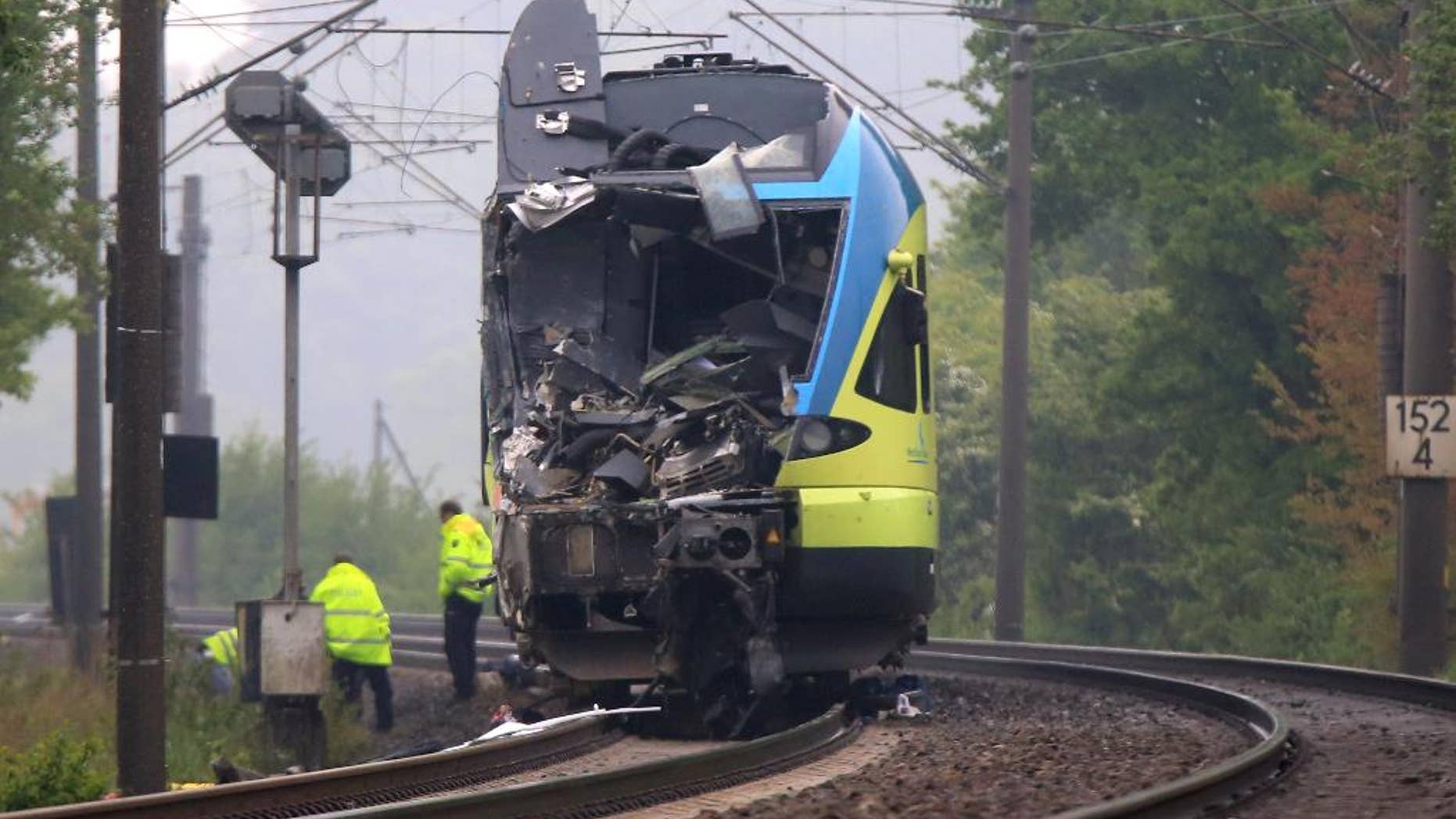 Workers are busy near the damaged train that hit a truck on a road crossing near Ibbenbueren, western Germany, Saturday, May 16, 2015. Police said two people have been killed and at least 20 others were injured in the accident. (Marcel Kusch/dpa via AP)