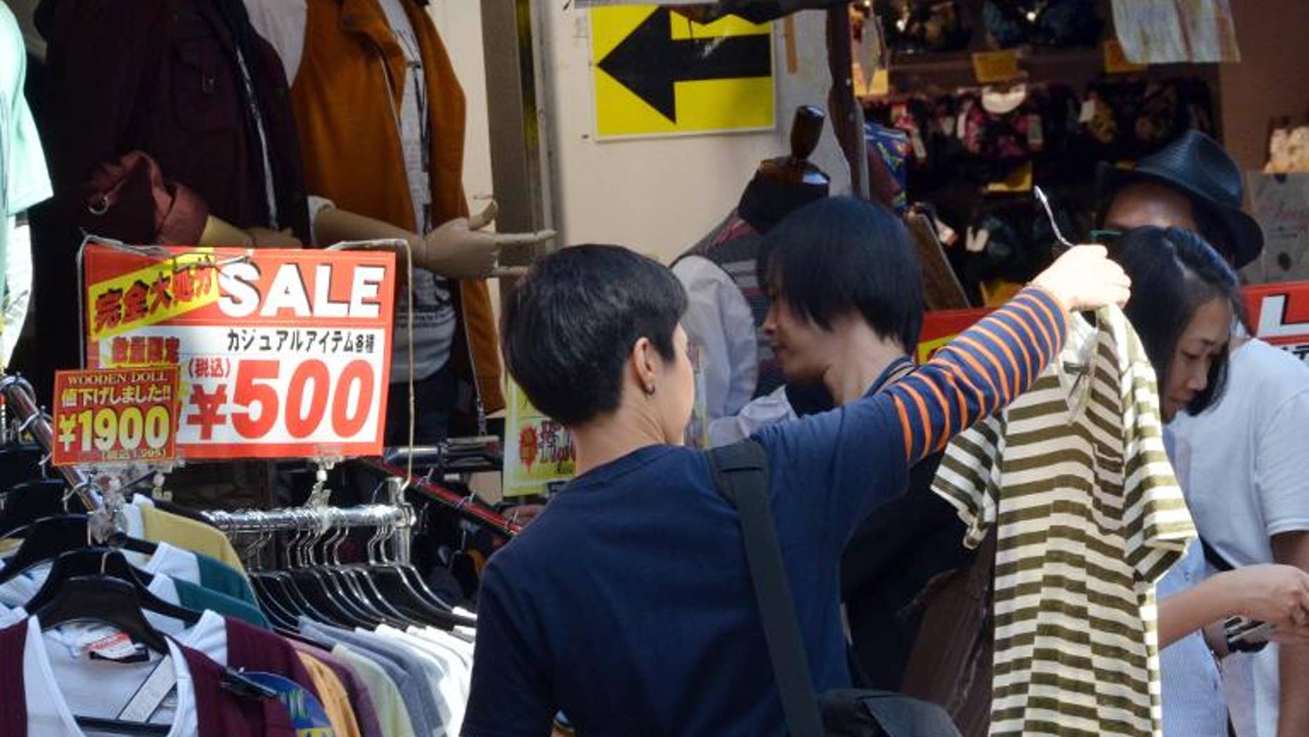 Shoppers look at clothing on sale outside a shop in Tokyo's Harajuku district, September 27, 2013