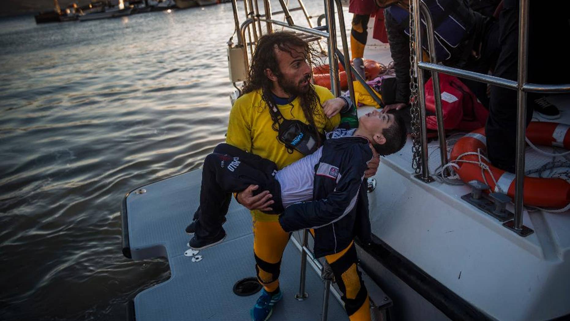 A volunteer carries a young boy after a boat with refugees and migrants sank while crossing the Aegean sea from Turkey to the Greek island of Lesbos, on Wednesday, Oct. 28, 2015. The condition of the child is not known. The Greek coast guard said it rescued 242 refugees or economic migrants off the eastern island of Lesbos Wednesday after the wooden boat they traveled in capsized, leaving at least three dead on a day when another 8 people drowned trying to reach Greece. (AP Photo/Santi Palacios)