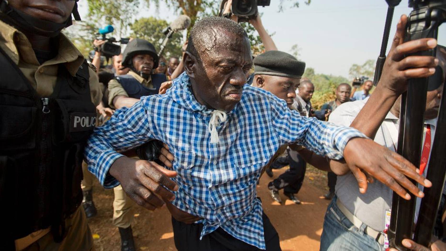 FILE - In this Monday, Feb. 22, 2016 file photo, Uganda's main opposition leader Kizza Besigye, center, is arrested by police and thrown into the back of a blacked-out police van, outside his home in Kasangati, Uganda. A spokesman for Uganda's judiciary said Saturday, May 14, 2016 that the main opposition leader Kizza Besigye has been flown to Moroto in the remote northeast of the country and charged with treason, a charge which attracts a maximum penalty of death upon conviction. (AP Photo/Ben Curtis, File)