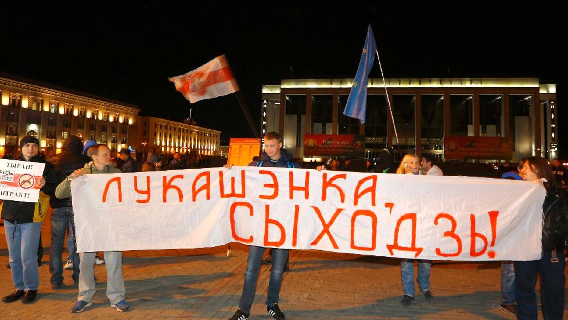 Belarusian opposition activists rally in the city center after presidential elections in Minsk, Belarus, late Sunday, Oct. 11, 2015. President Alexander Lukashenko was expected to win a fifth term in Sunday's election with ease, but he said anything much less than 80 percent of the vote would be a sign that his support was slipping. The authoritarian leader faced no serious competition in the election, which was boycotted by the opposition. The sign reads "Lukashenko, go away!" (AP Photo/Sergei Grits)