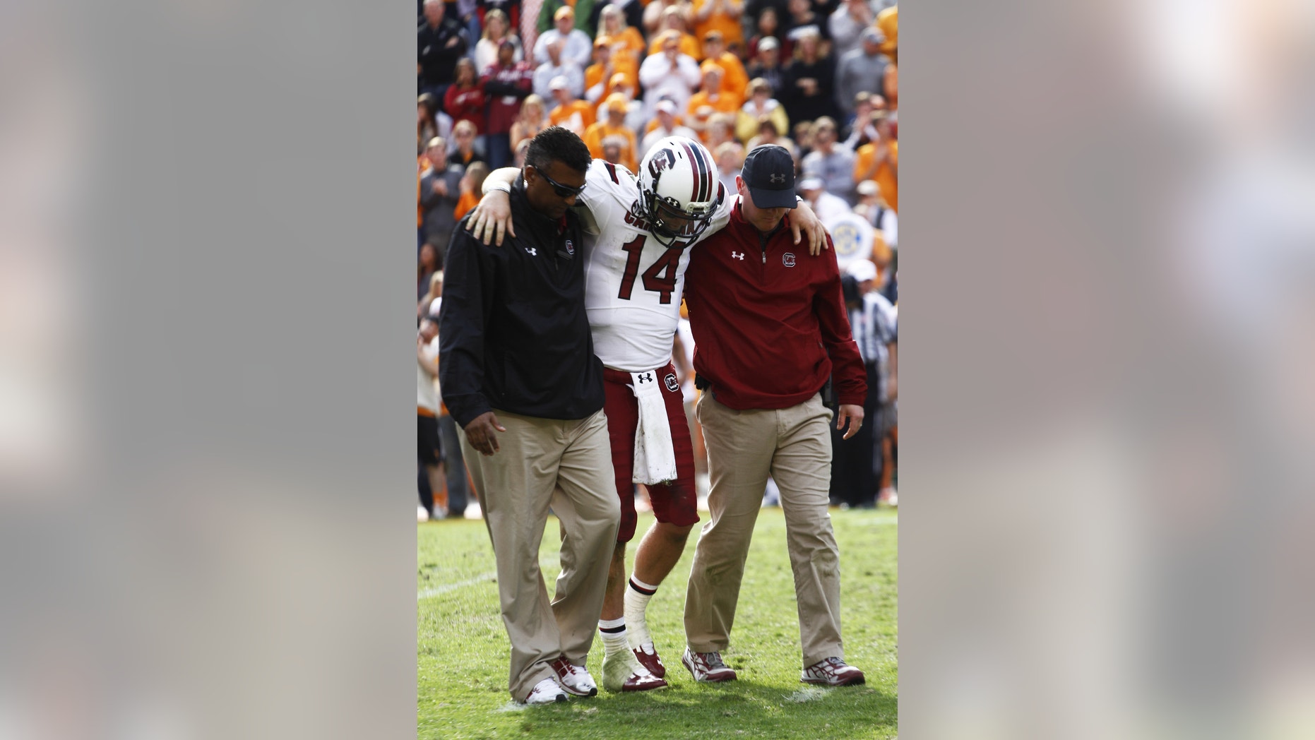 South Carolina quarterback Connor Shaw (14) is helped from the field after being injured in the fourth quarter of an NCAA college football game against Tennessee on Saturday, Oct. 19, 2013 in Knoxville, Tenn. (AP Photo/Wade Payne)