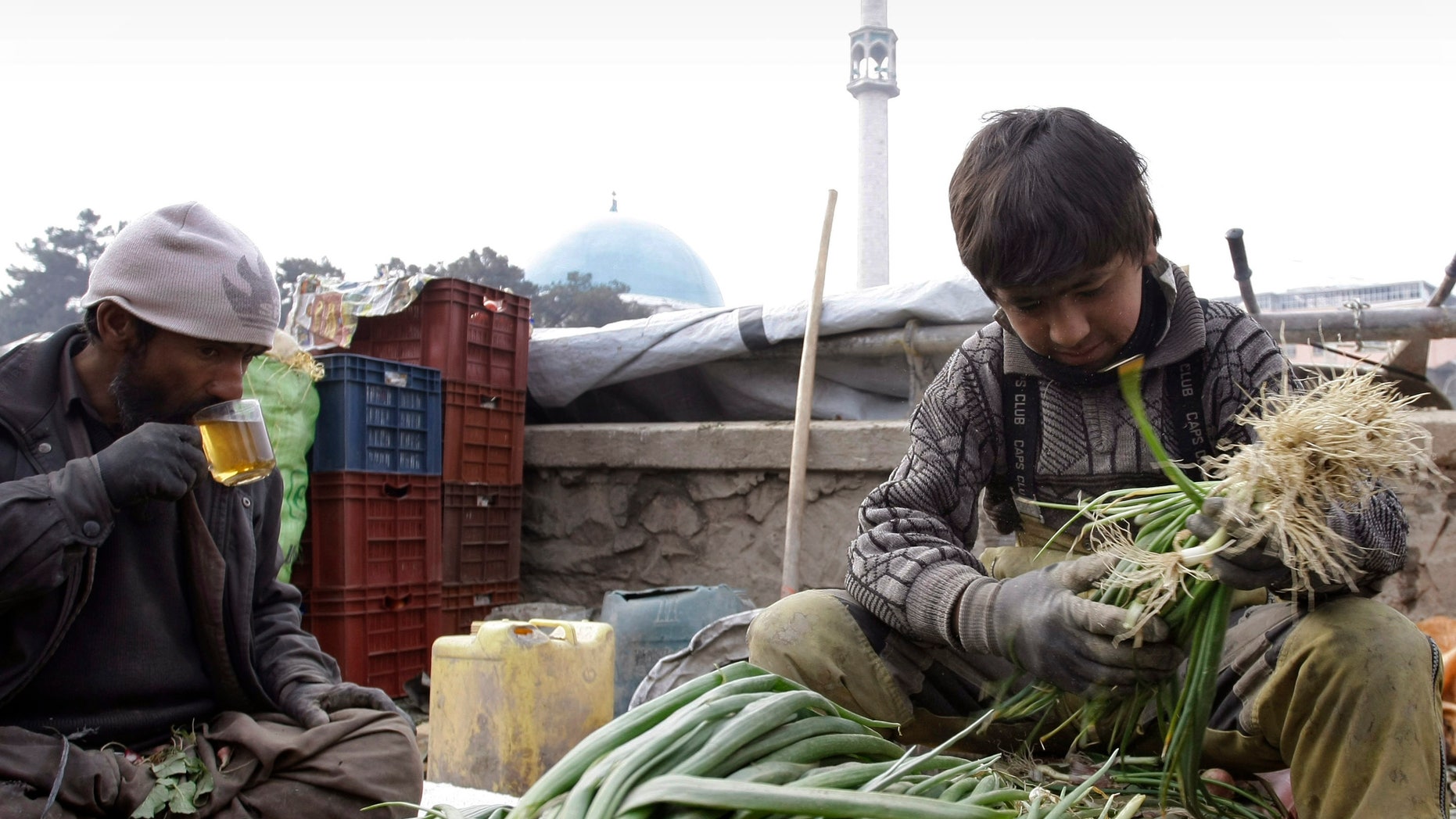 An Afghan vendor, right, sorts out vegetables as his father drinks tea during sorting of vegetable in Kabul, Afghanistan on Wednesday, Feb. 13, 2013. (AP Photo/Musadeq Sadeq)