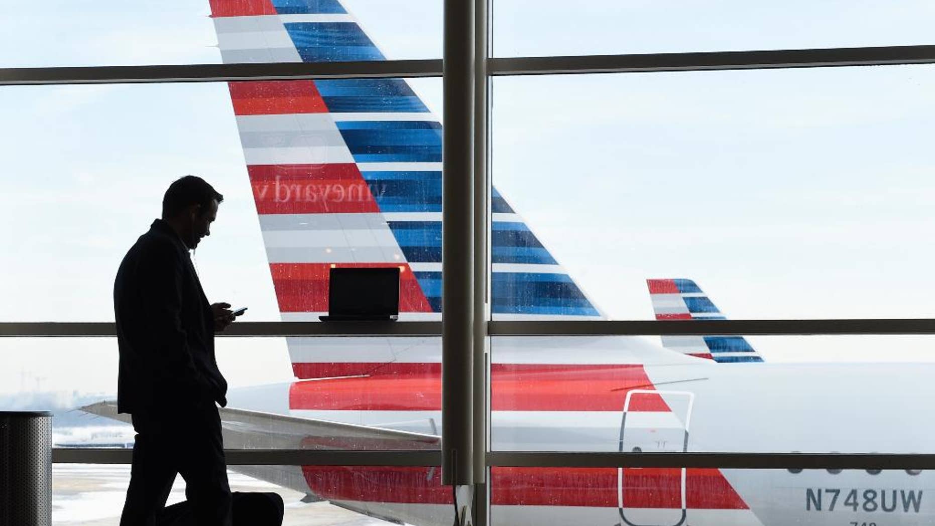 FILE - In this Jan. 25, 2016, file photo, a passenger talks on the phone as American Airlines jets sit parked at their gates at Washington's Ronald Reagan National Airport. American Airlines has agreed to pay $200 million for a stake in China Southern Airlines, the biggest of China's three major state-owned carriers, in a bid for a bigger share of the country's growing travel market. (AP Photo/Susan Walsh, File)