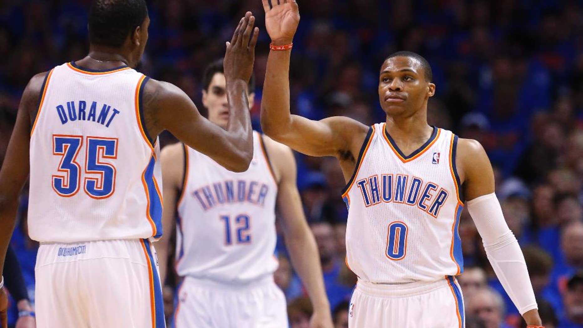 Oklahoma City Thunder guard Russell Westbrook (0) high-fives teammate Kevin Durant (35) in the first quarter of Game 7 of an opening-round NBA basketball playoff series against the Memphis Grizzlies in Oklahoma City, Saturday, May 3, 2014. (AP Photo/Sue Ogrocki)