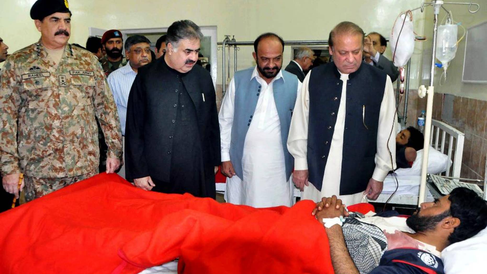 In this photo provided by Pakistan's Press Information Department, Pakistan's Prime Minister Nawaz Sharif, right, talks to a survivor of an overnight attack on the Police Training Academy, with Pakistan army chief Gen. Raheel Sharif, left, at a local hospital in Quetta, Pakistan, Tuesday, Oct. 25, 2016. Militants wearing suicide vests stormed a Pakistani police academy in the southwestern city of Quetta overnight, killing dozens of people, mostly police cadets and recruits, and waging a ferocious gun battle with troops that lasted into early hours Tuesday. (AP Photo/Press Information Department)