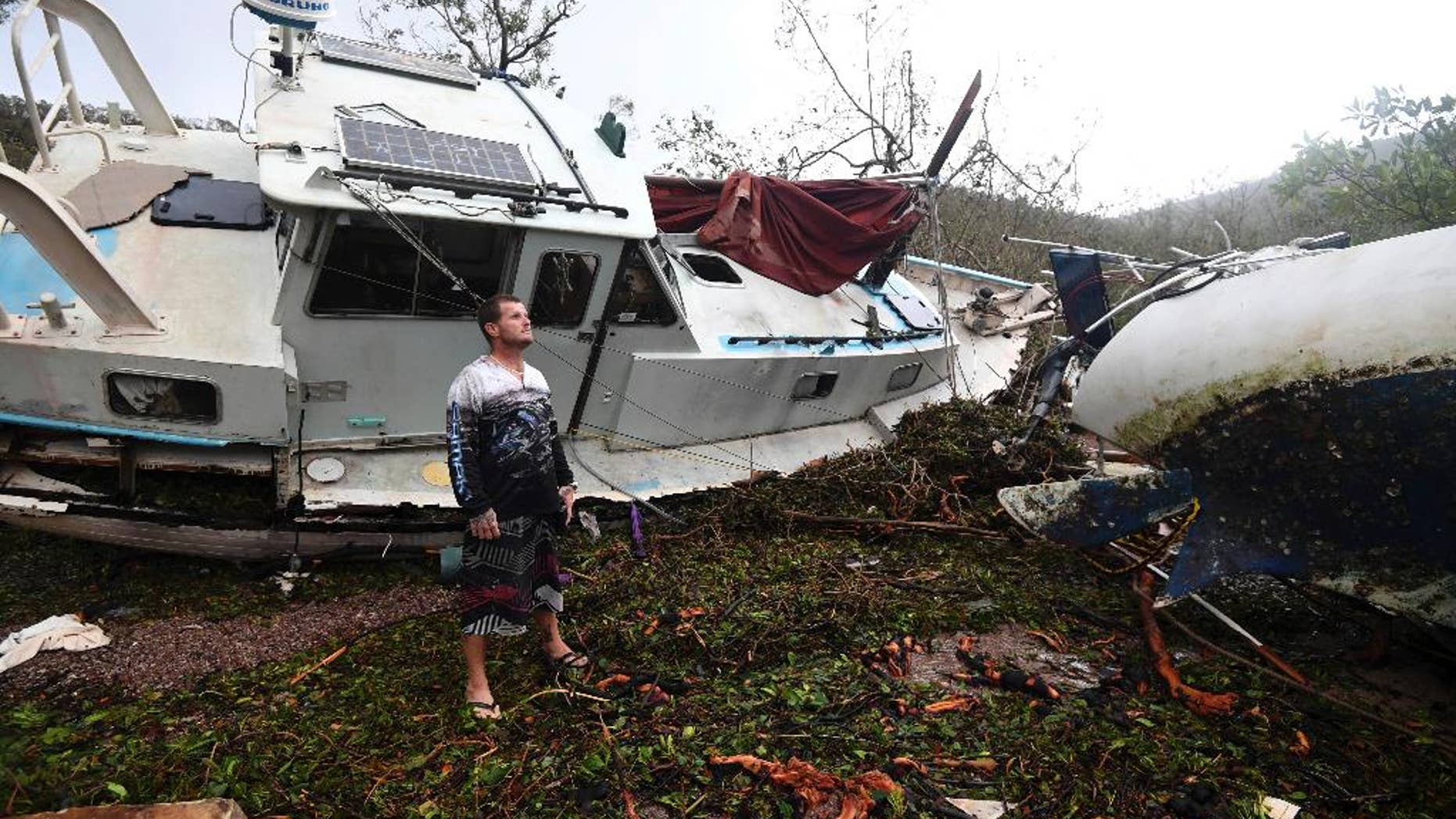 Bradley Mitchell inspects the damage to his uncle's boat after it smashed against the bank at Shute Harbour, Airlie Beach, Australia, Wednesday, March 29, 2017. Cyclone Debbie, which slammed into the coast of Queensland state on Tuesday with winds up to 260 kilometers (160 miles) an hour, weakened quickly as it moved inland and was downgraded to a tropical low by Wednesday morning. (Dan Peled/AAP Image via AP)